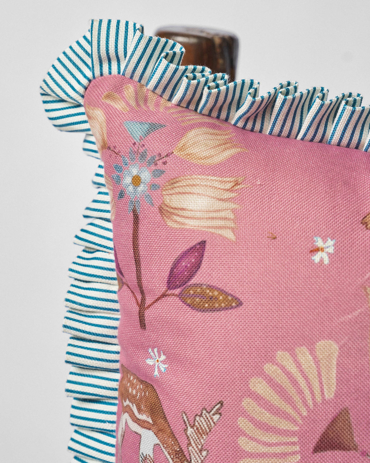 Close-up of Deer Dance Cushion showing flower motifs and a teal striped frill.