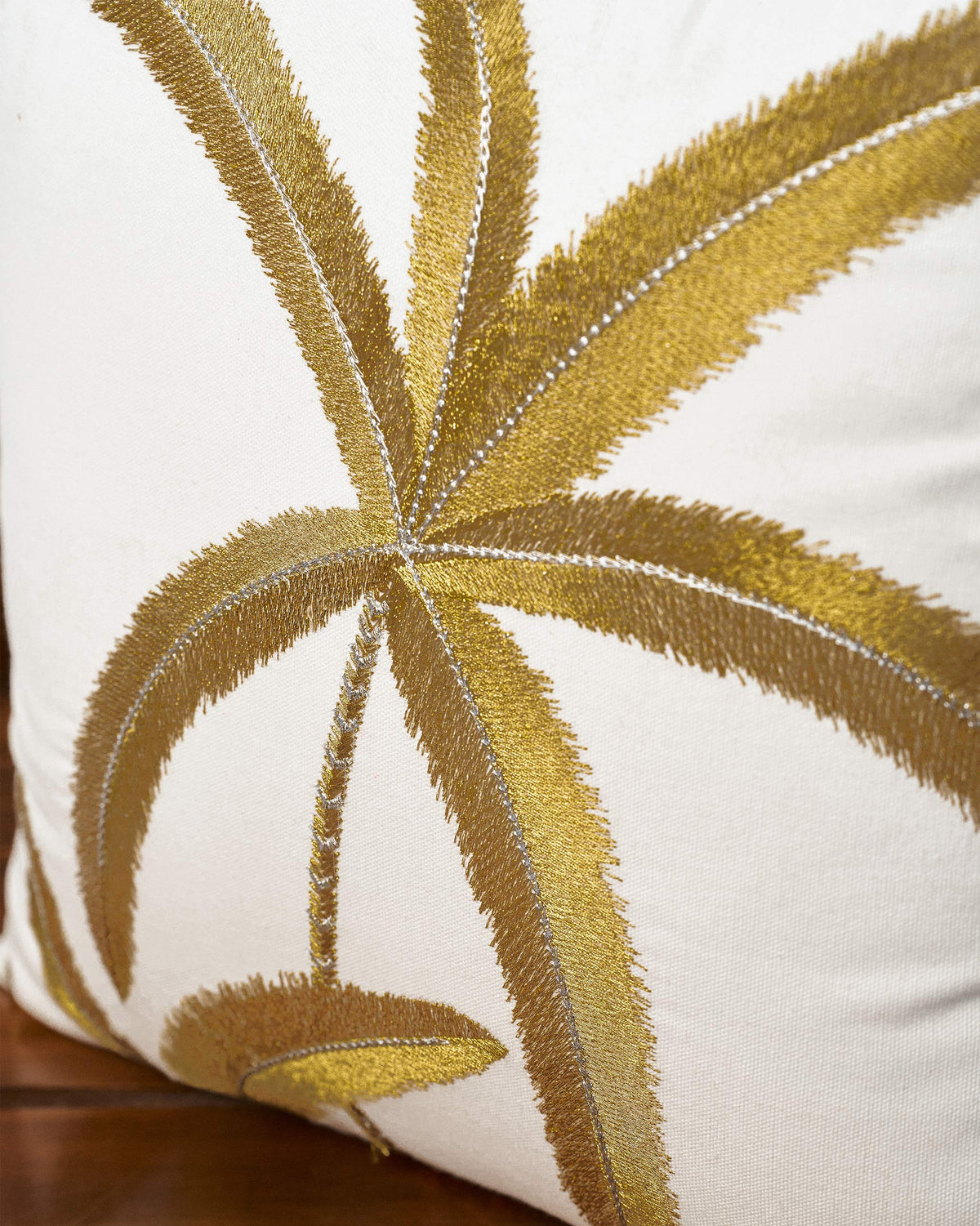 Close-up of Palm Dance cushion cover showing gold embroidered palm leaves.