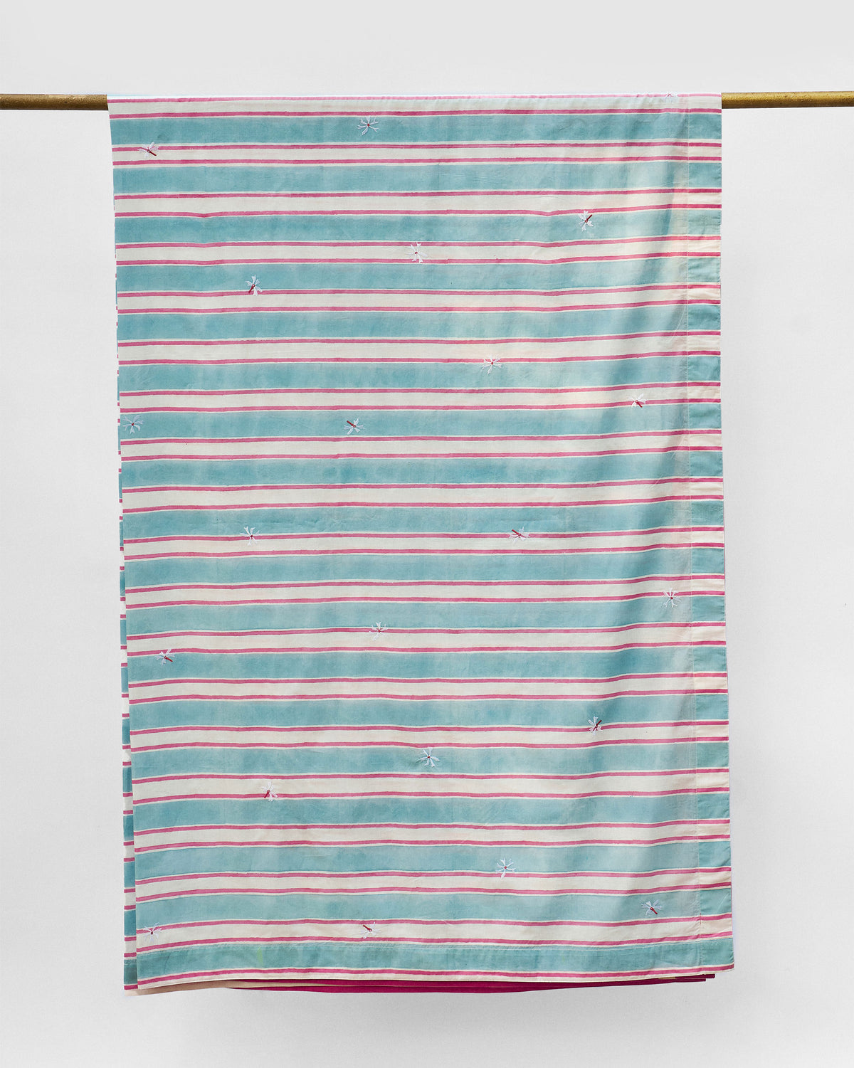 Parijat table cover in blue and pink stripes with small embroidered motifs.