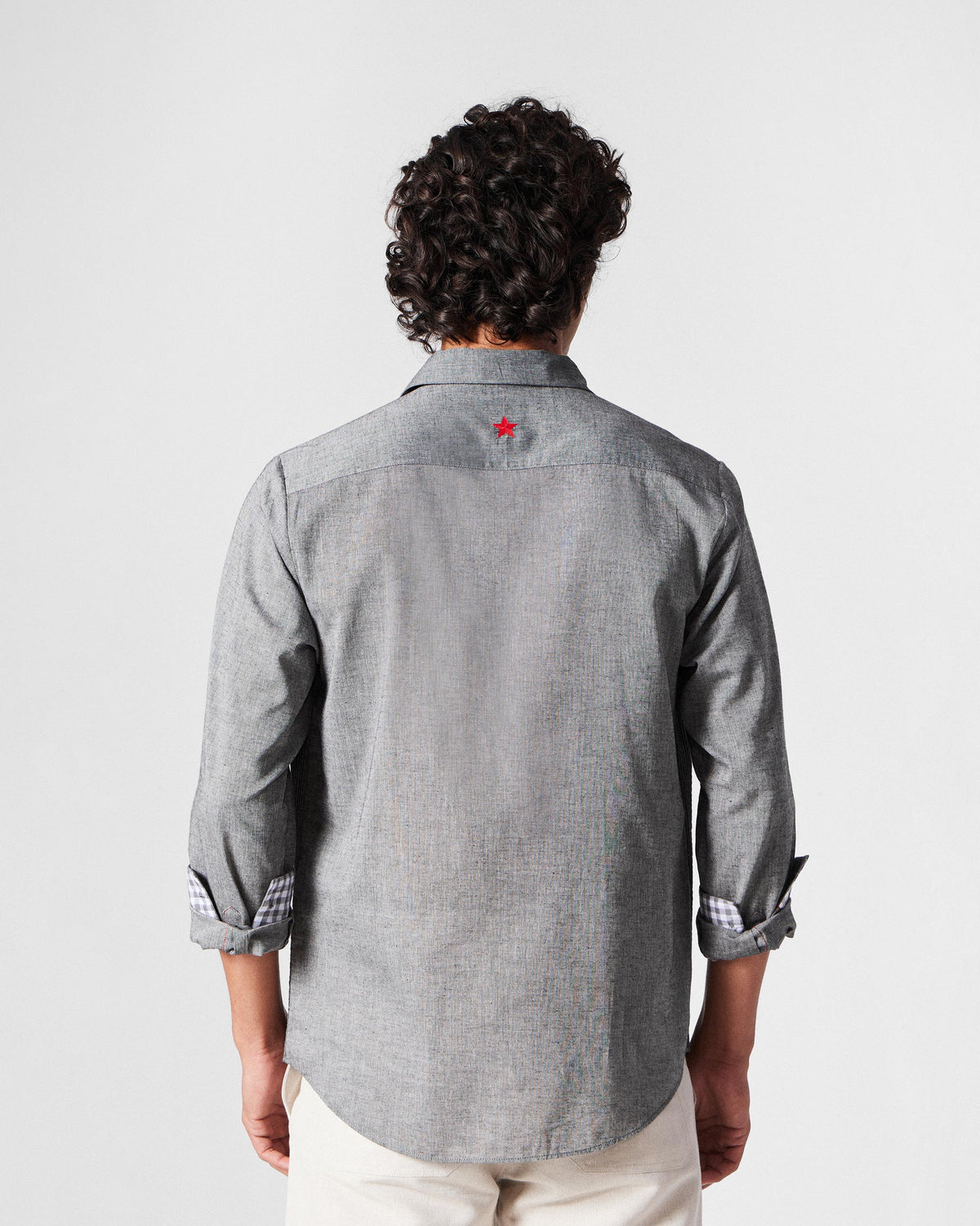 Back of a charcoal Nava shirt with a red embroidered star on the yoke.