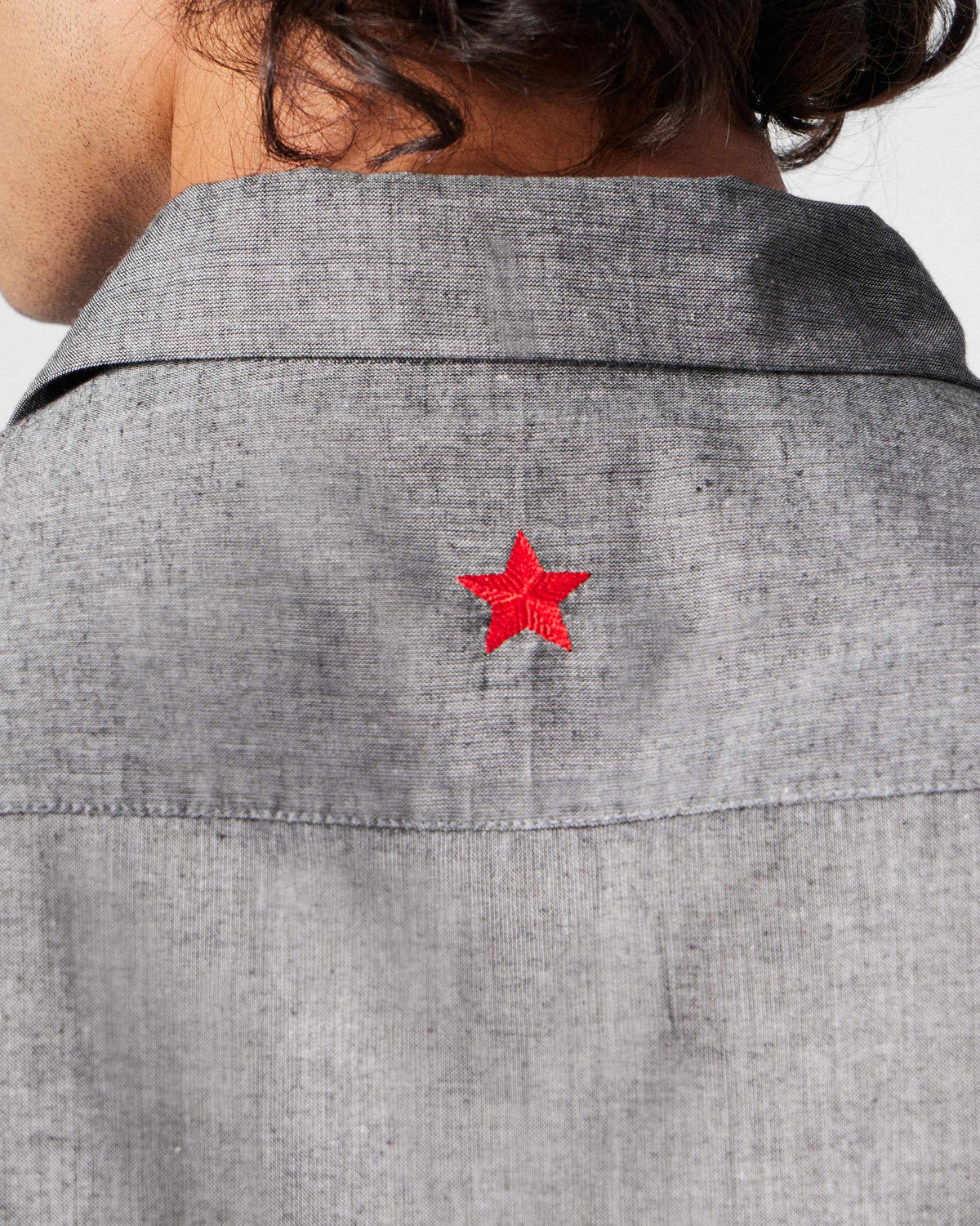 Close-up of the red embroidered star on the back yoke of a charcoal Nava shirt.