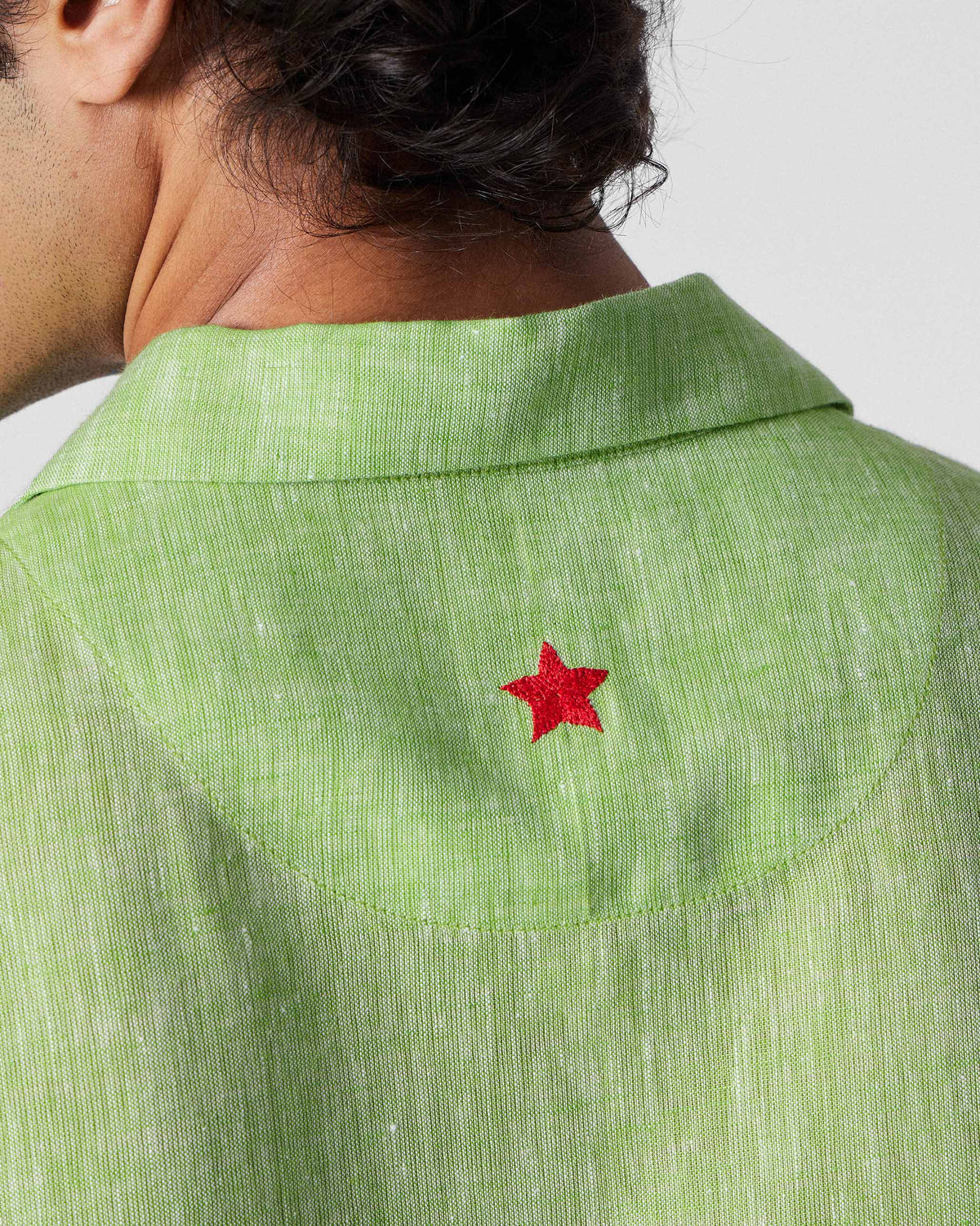 Close-up of a red star on the back of a light green Mistari shirt.