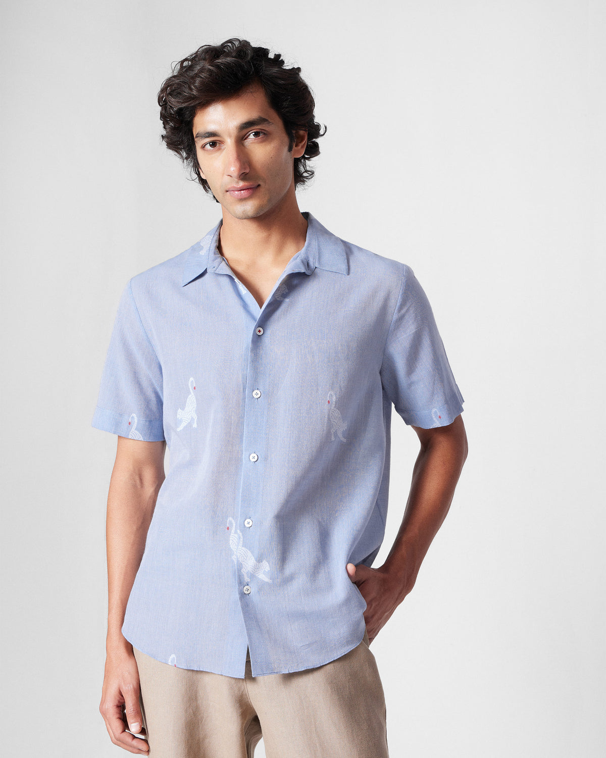 Person wearing a light blue half-sleeve shirt with white animal motifs.