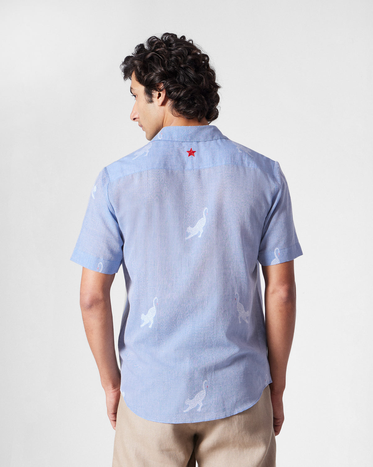 Back of a light blue half-sleeve shirt with a red star at the yoke.