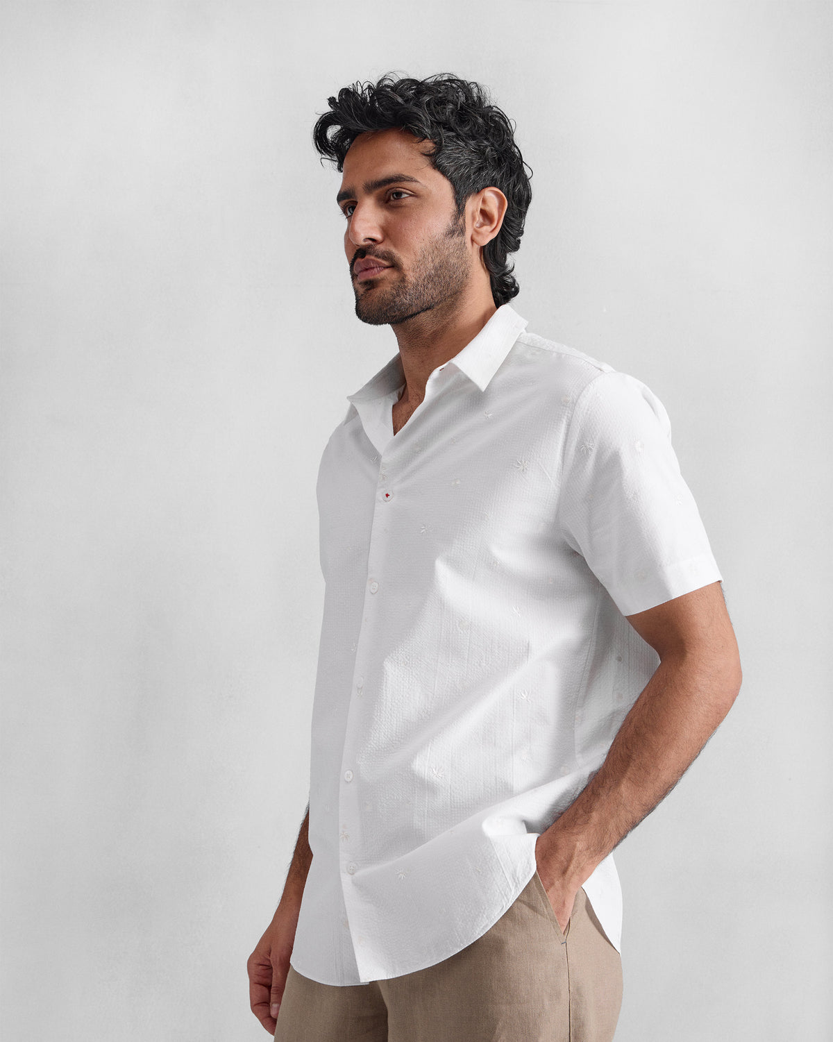 Side view of a white embroidered half sleeve shirt worn by a person.