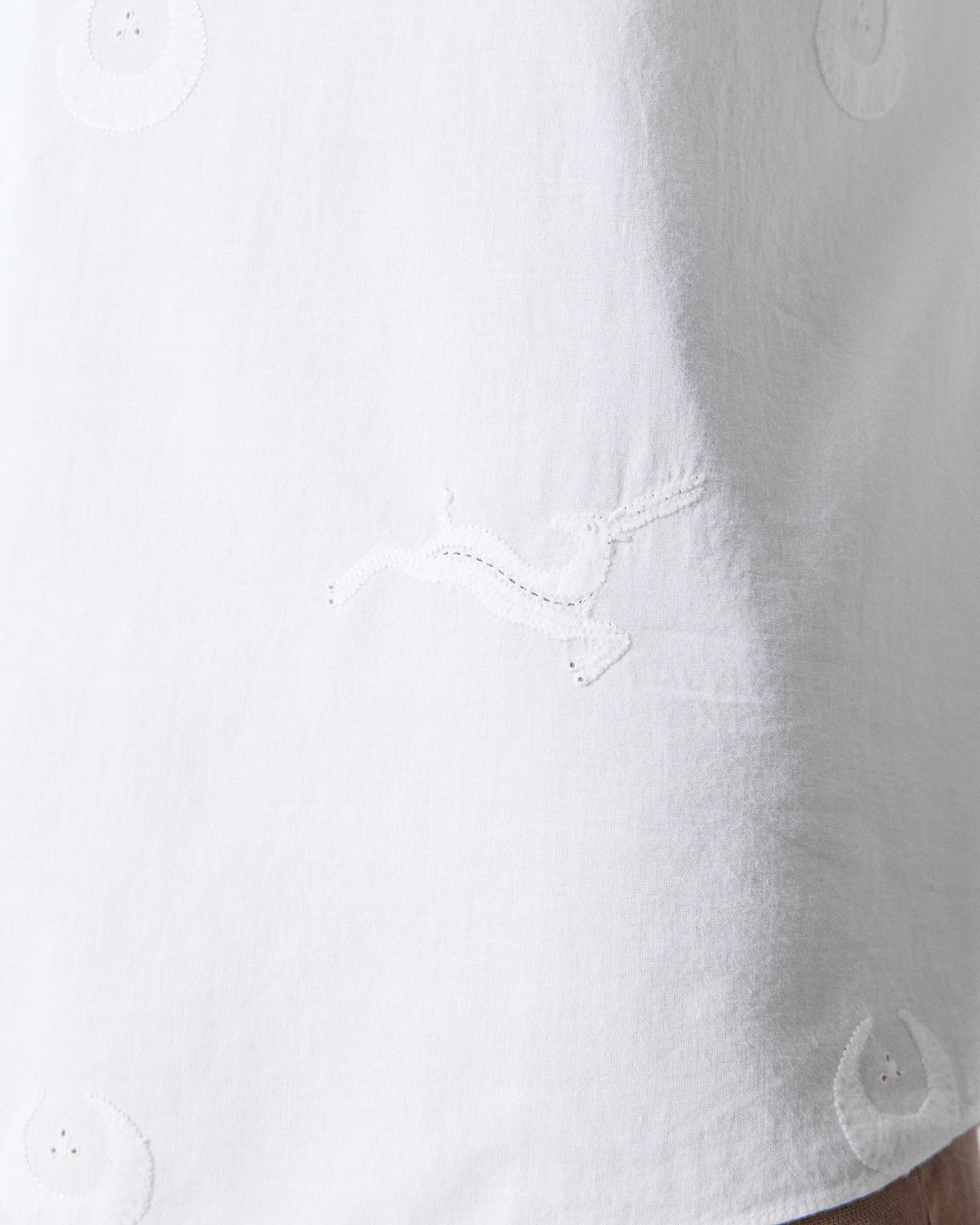 Close-up of a white Basalt shirt with a leaping hare embroidery.