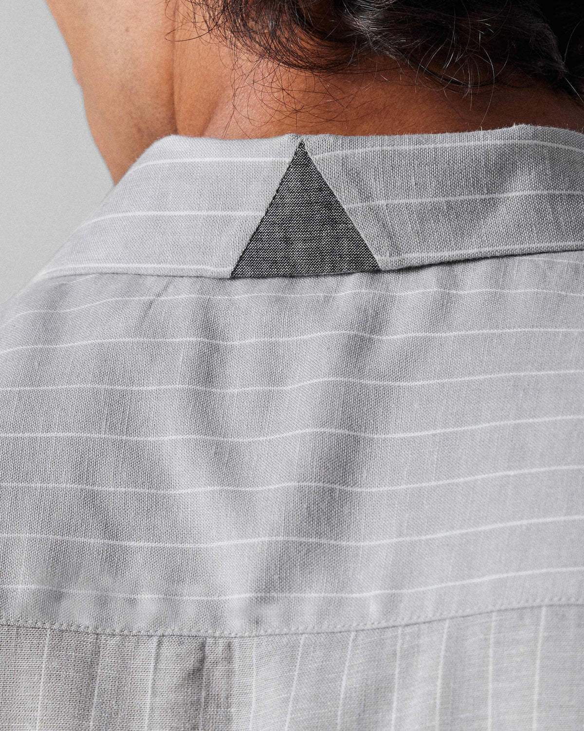 Close-up of the triangular collar patch on a charcoal striped Silas Shirt.