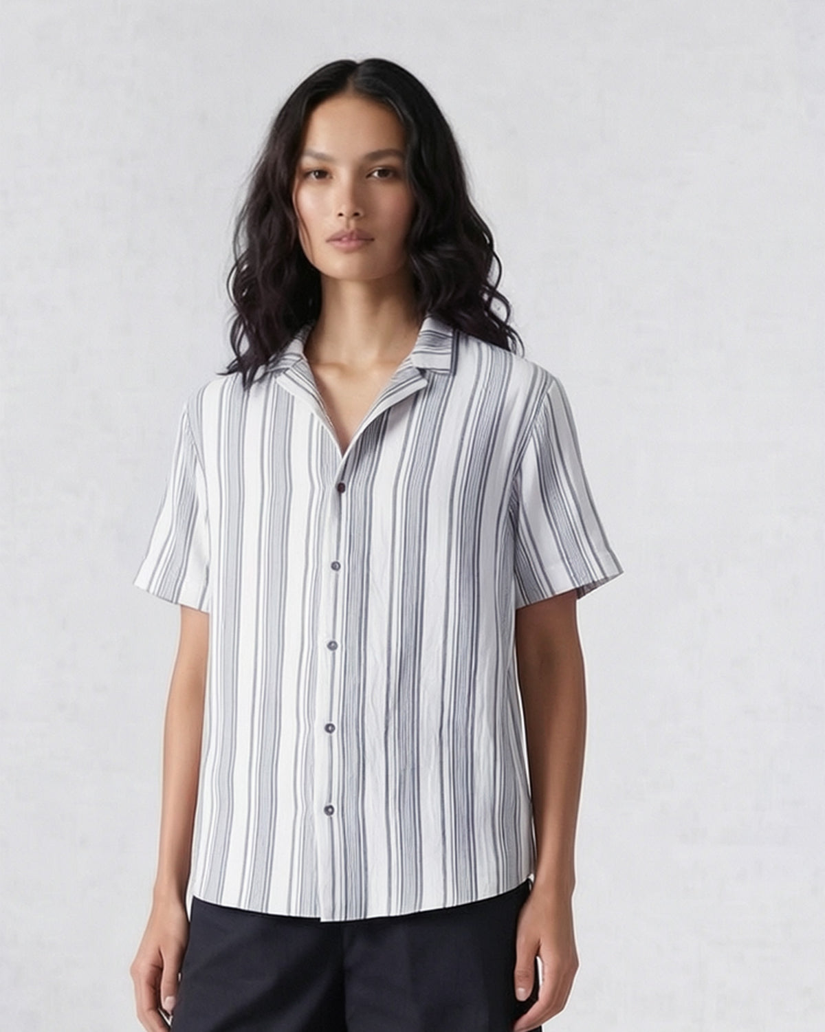 Person wearing a charcoal and ivory striped Mistari shirt with a camp collar.