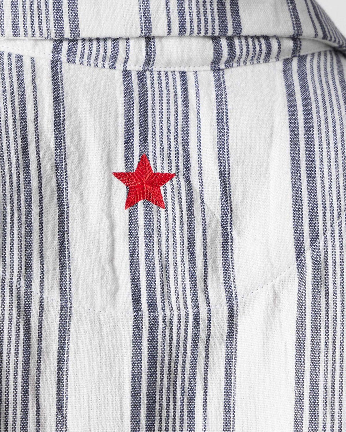 Close-up of a red embroidered star on charcoal and ivory striped Mistari shirt fabric.