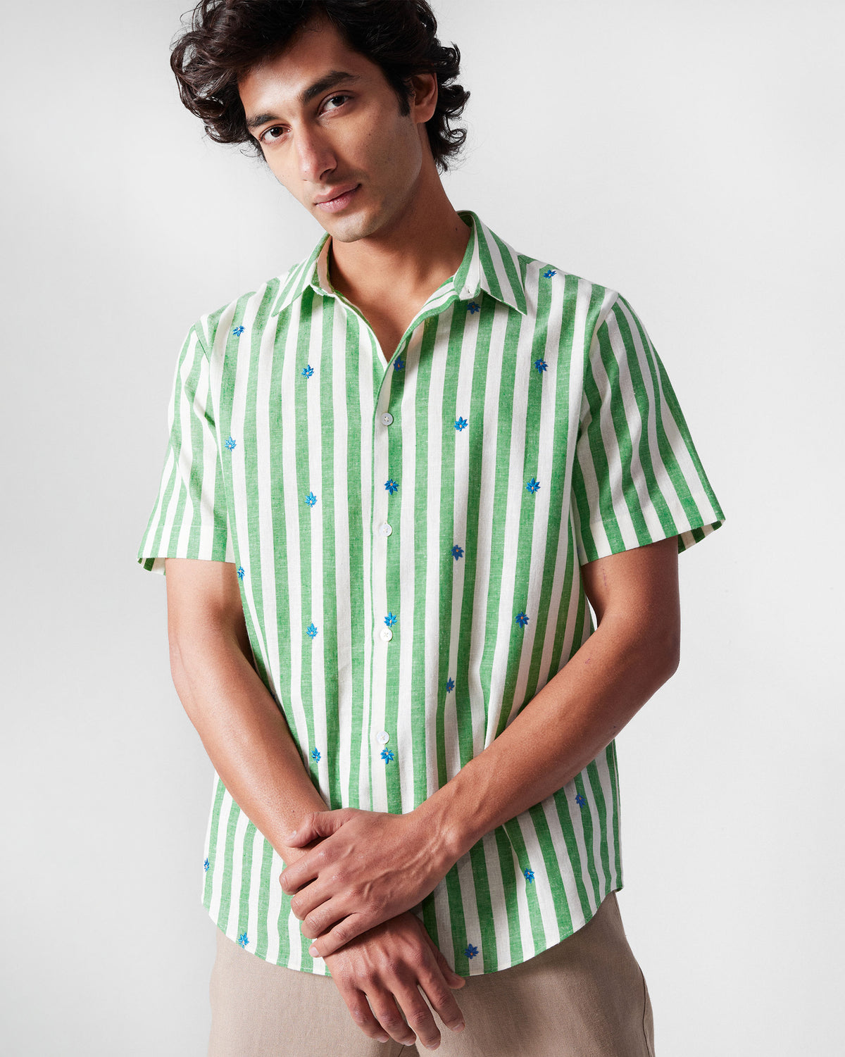 Person wearing a green-and-white striped half-sleeve shirt with blue leaf embroidery.