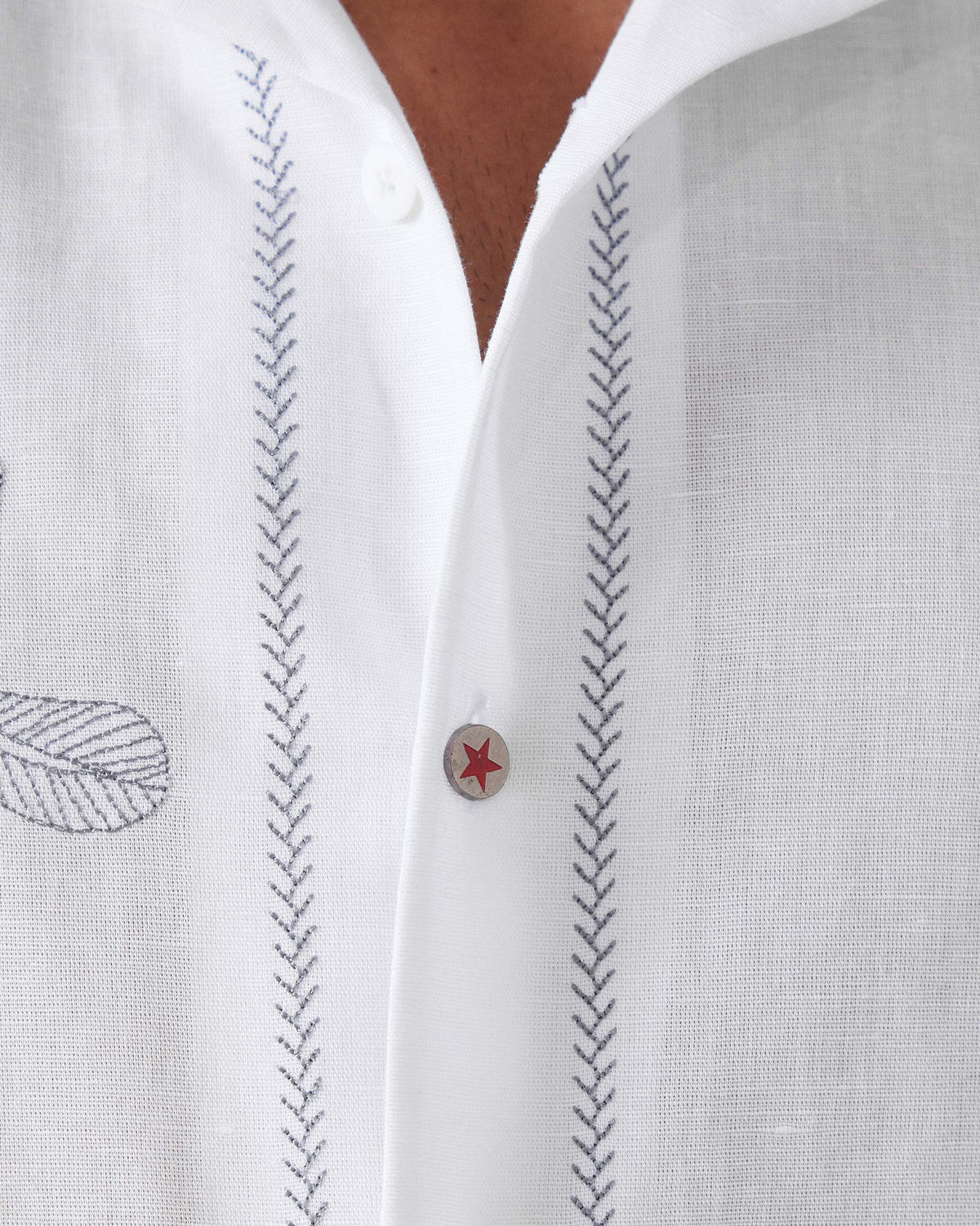 Close-up of a white Delta shirt showing zig-zag stitchwork and a red star button.