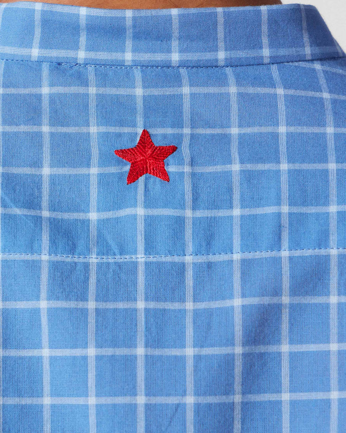 Close-up of a red star embroidery on the back of a blue checked Nysa kurta.