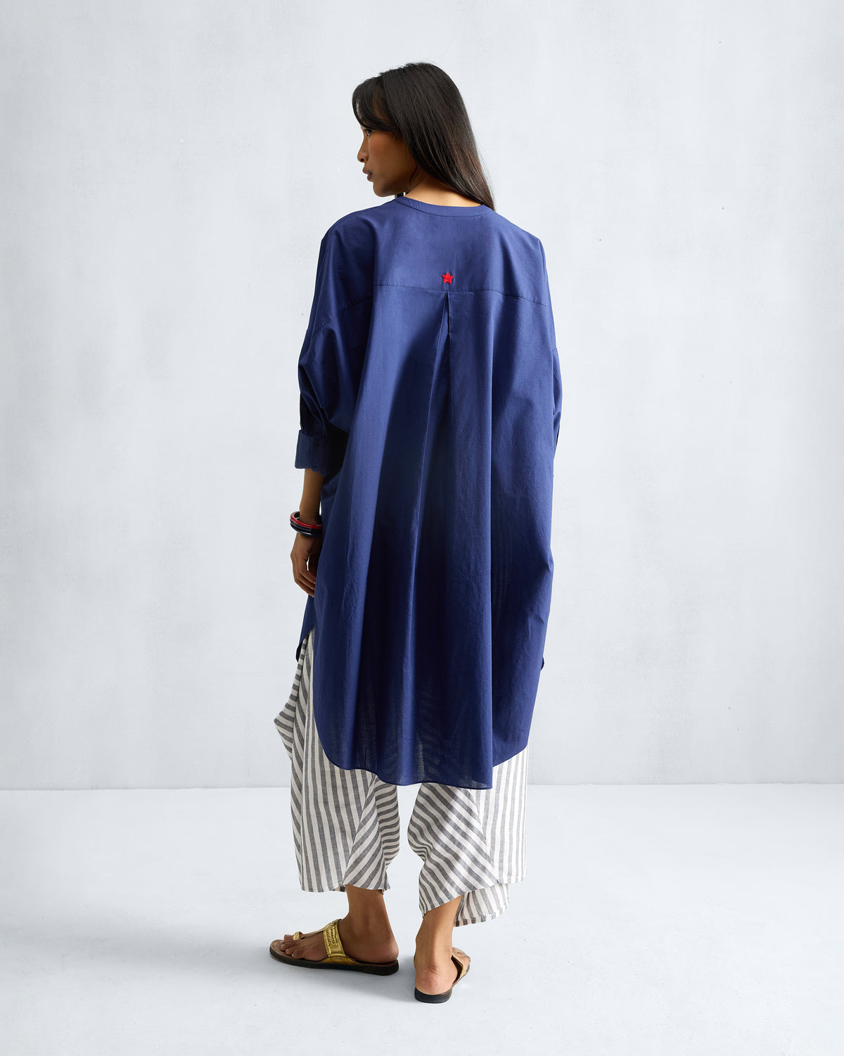 Back of an ink blue Lazy Sunday tunic with a pleated yoke and red star.