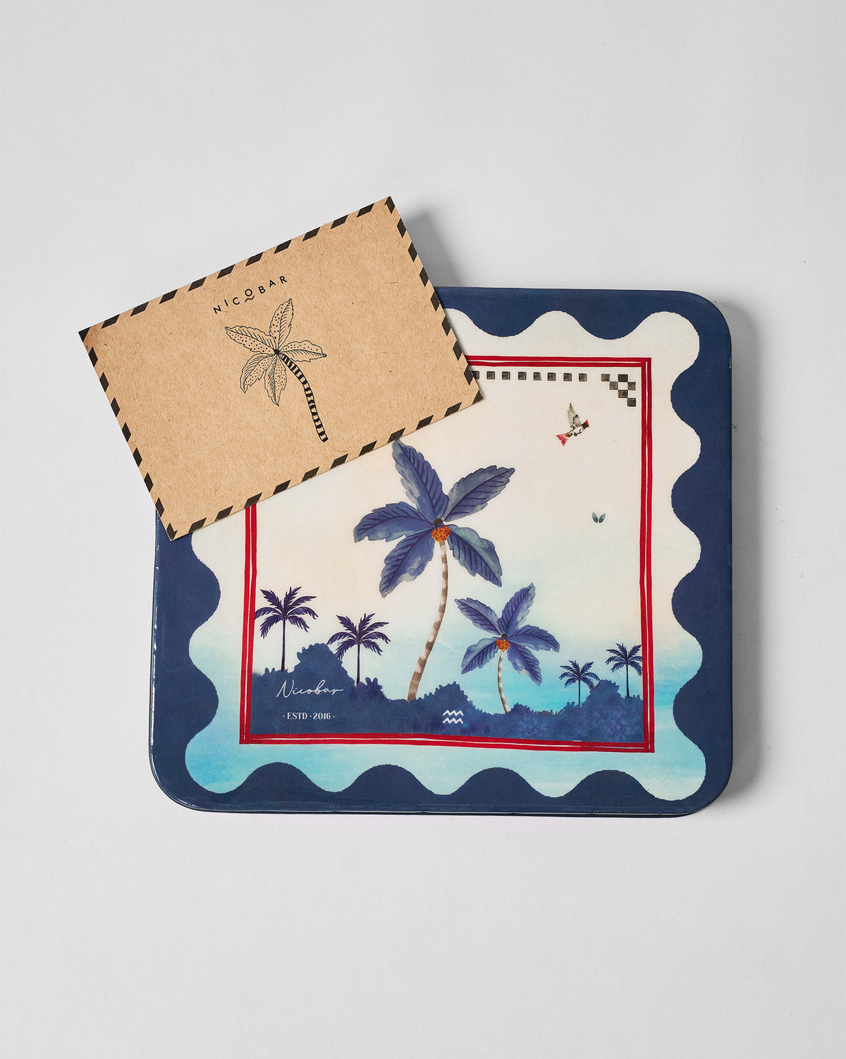 Kandy Stripes Barware Gift Set tin with palm print and a Nicobar kraft envelope.