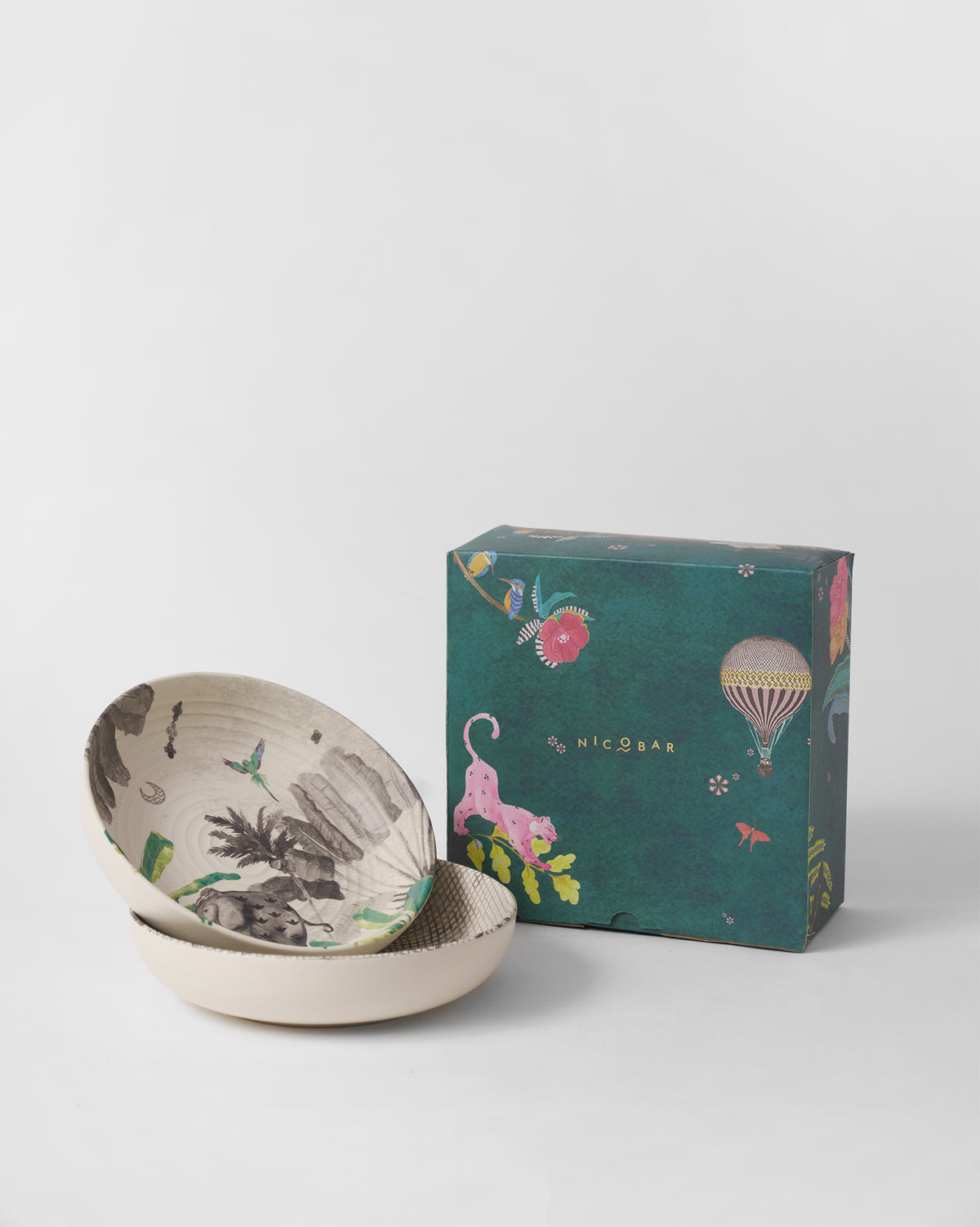 Haathi shallow bowls stacked beside a teal illustrated Nicobar gift box.