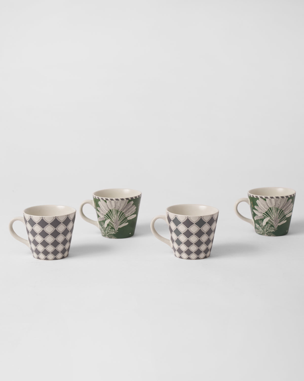 Staggered row of Kandy espresso mugs in diamond and palm designs.