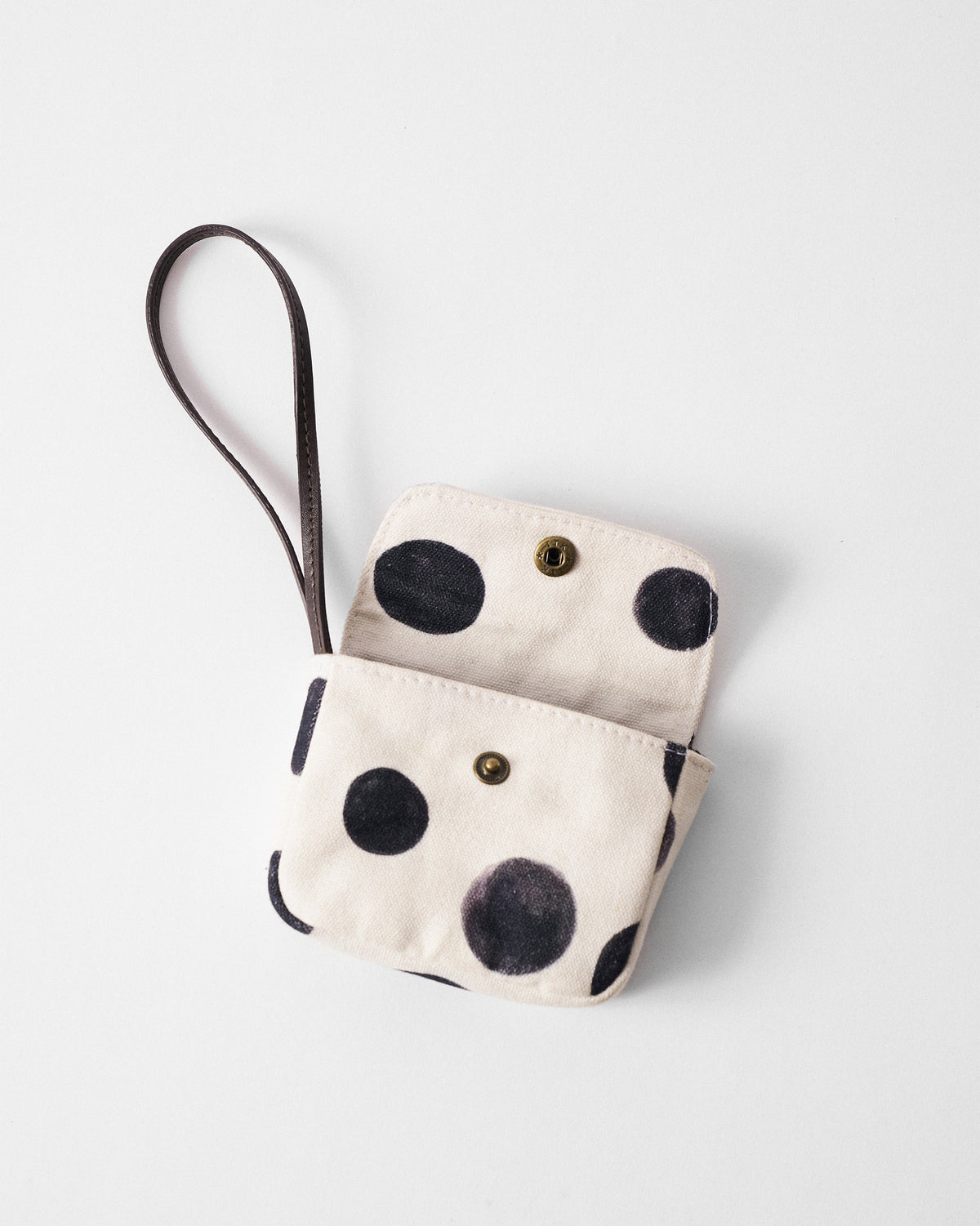 Open ivory Polka Coin Pouch with charcoal polka dots and a leather wrist strap.