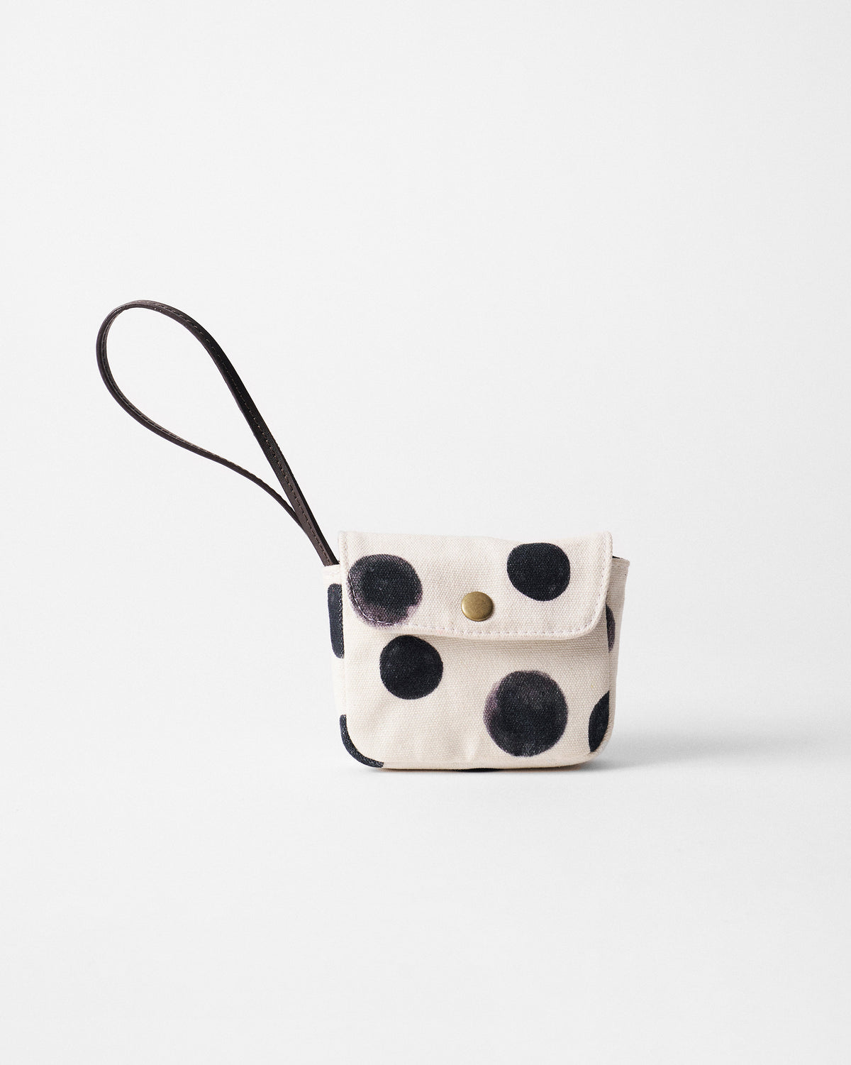 Ivory Polka Coin Pouch with charcoal dots, a brass snap, and a leather wrist strap.