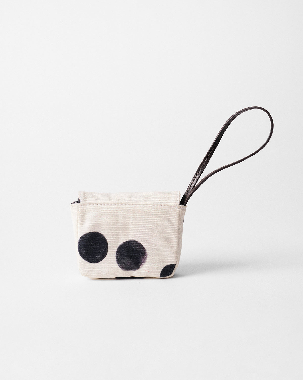 Ivory Polka Coin Pouch with charcoal polka dots and a brown leather strap.