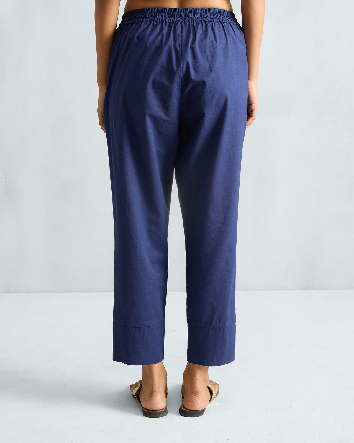 Back of ink blue narrow pants with an elasticated waistband and wide hems.