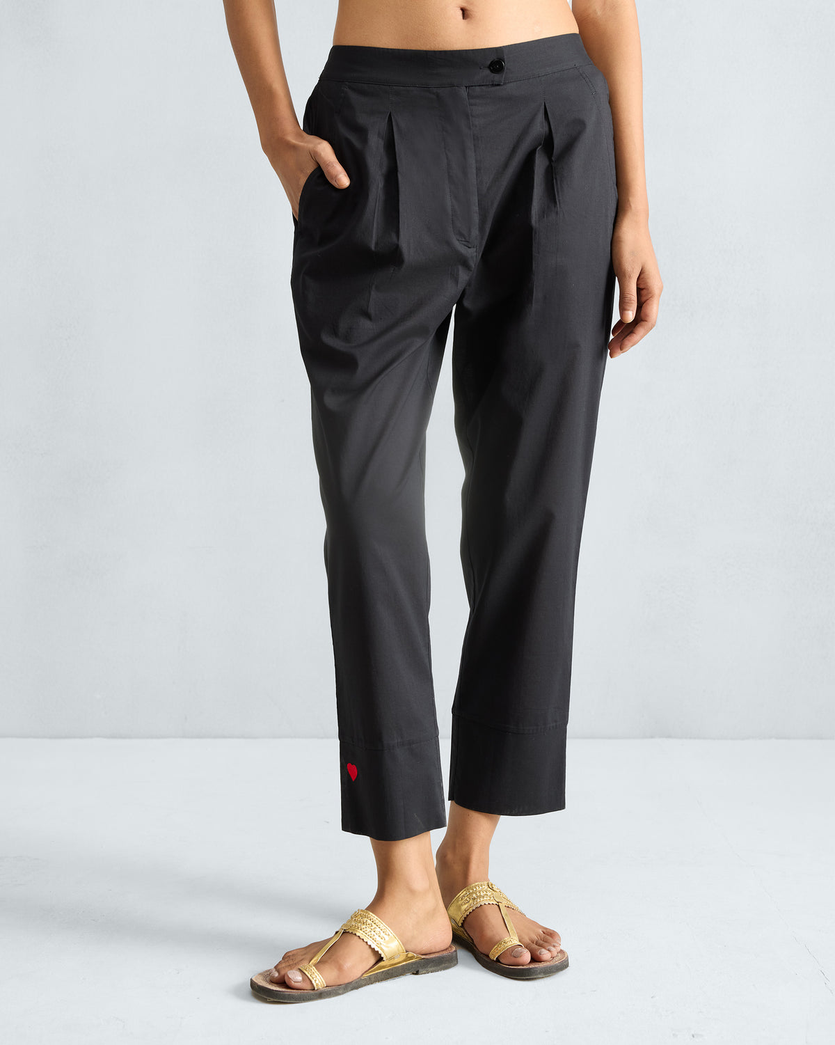 Black Narrow pants with front pleats and a red embroidered heart at the cuff.