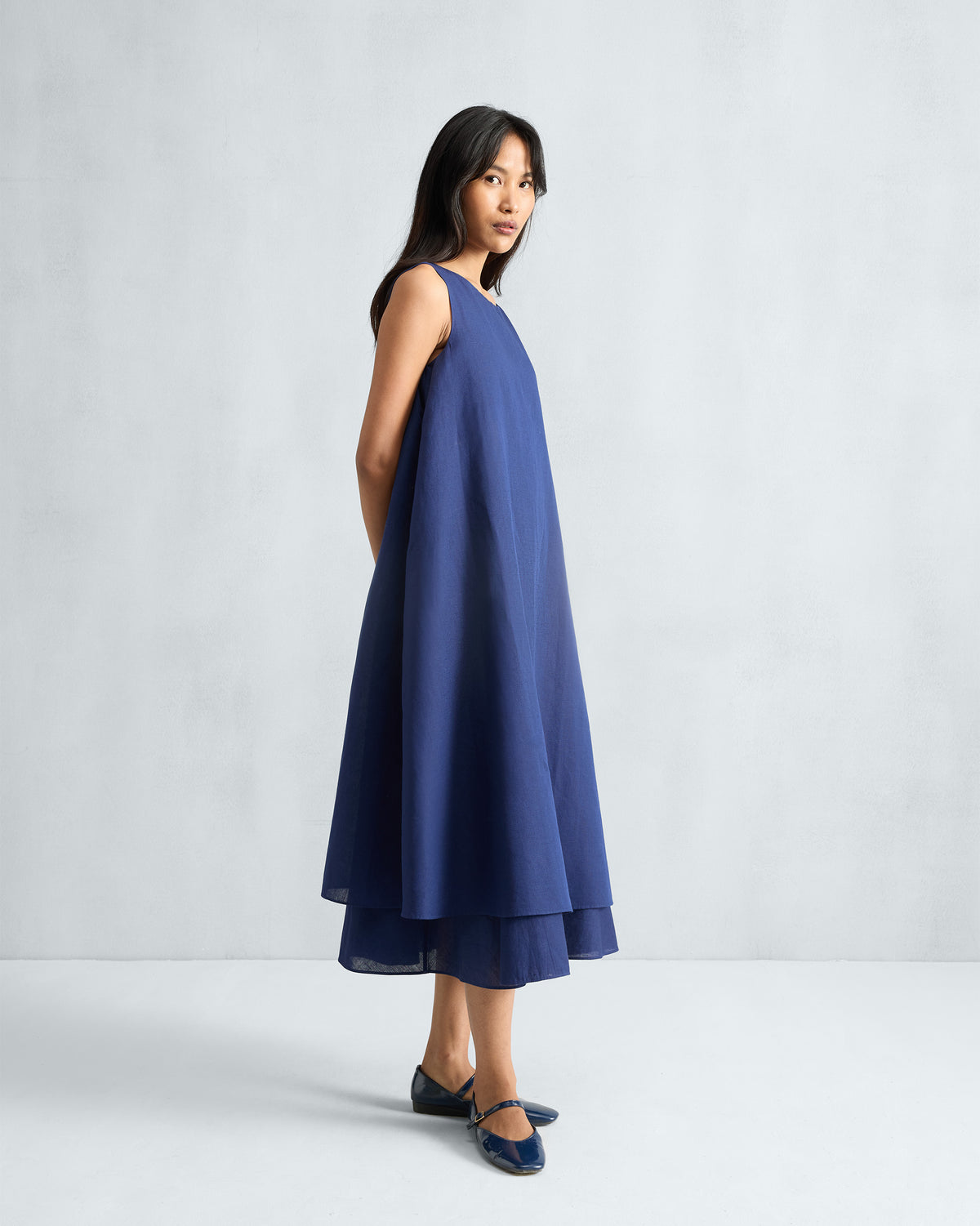 Side view of an ink blue Double Layer Dress with a voluminous hem.