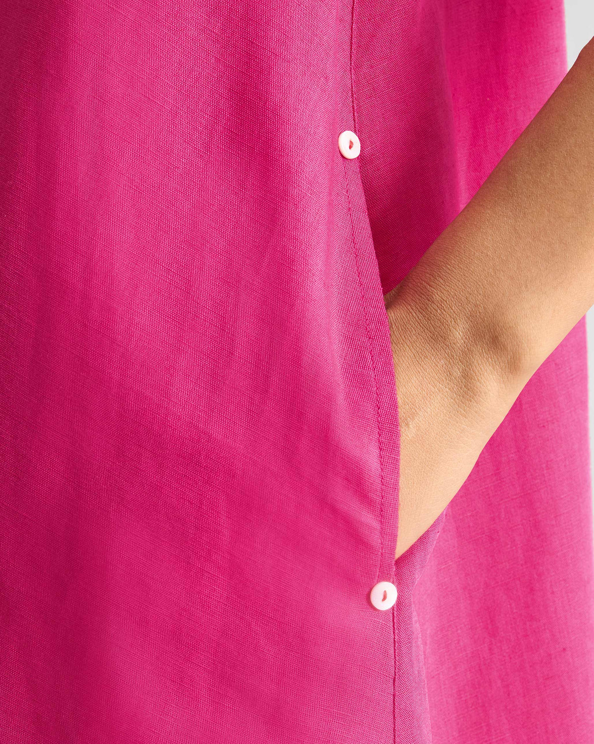 Close-up of a fuchsia dress side pocket with white buttons.