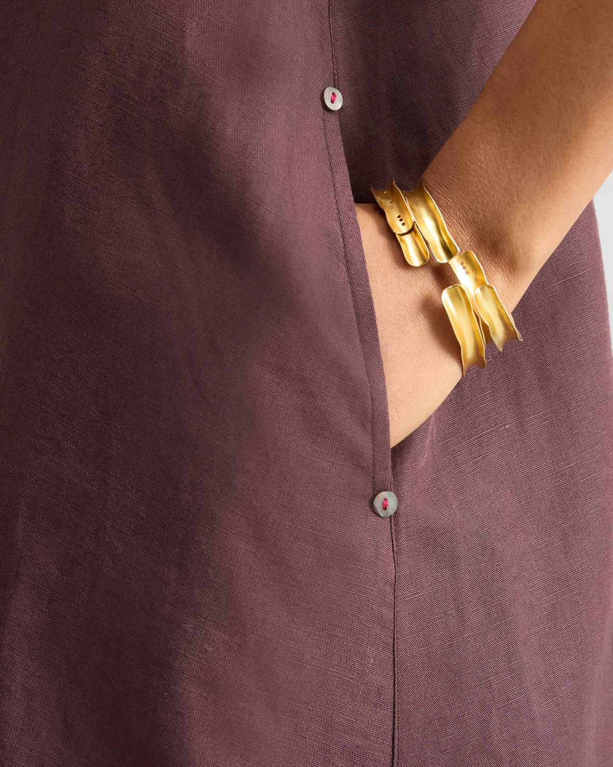 Close-up of a chocolate plum Double Layer Dress pocket with pink-stitched buttons.