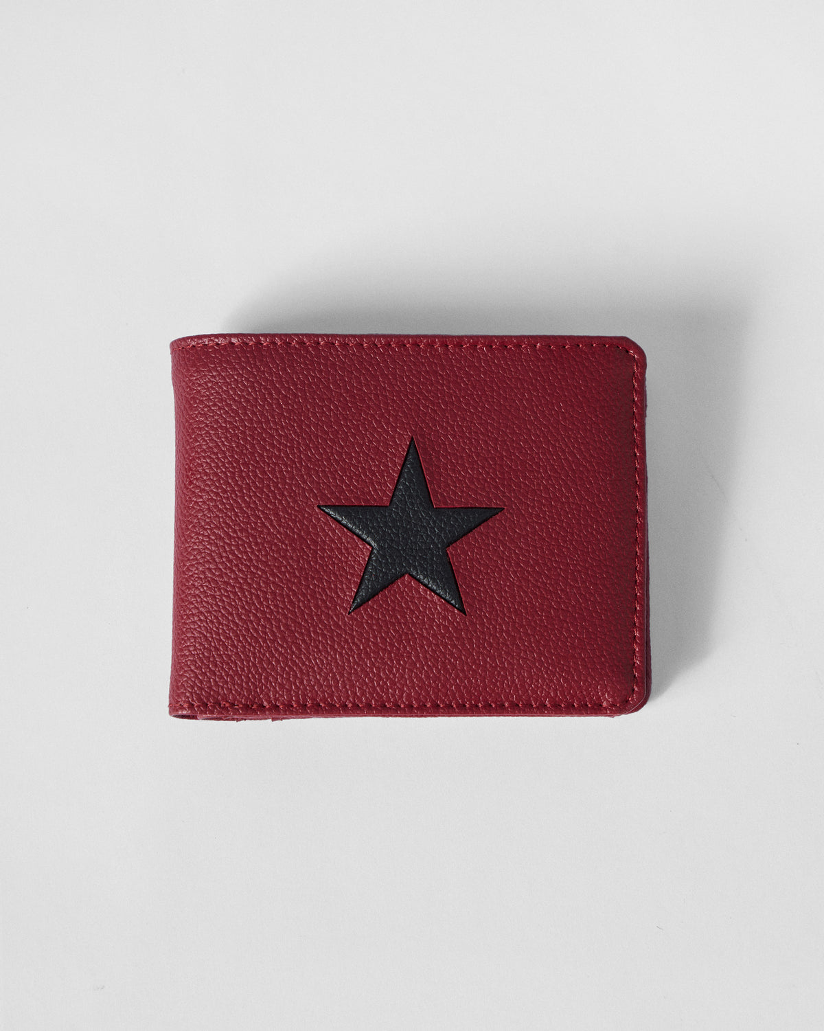 Closed red bi-fold wallet with a black star on pebbled leather.
