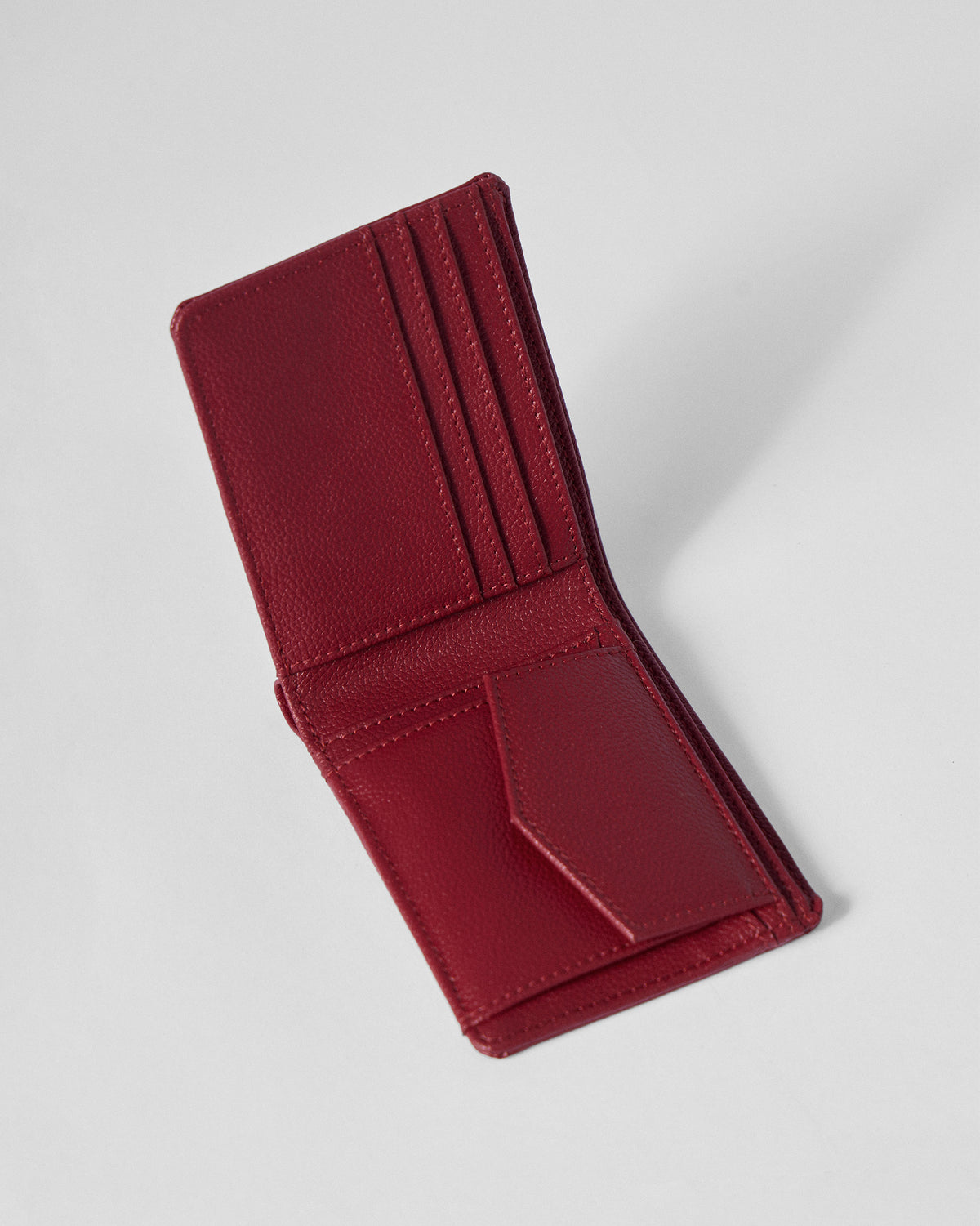 Open red bi-fold wallet with card slots and a flapped coin pocket.