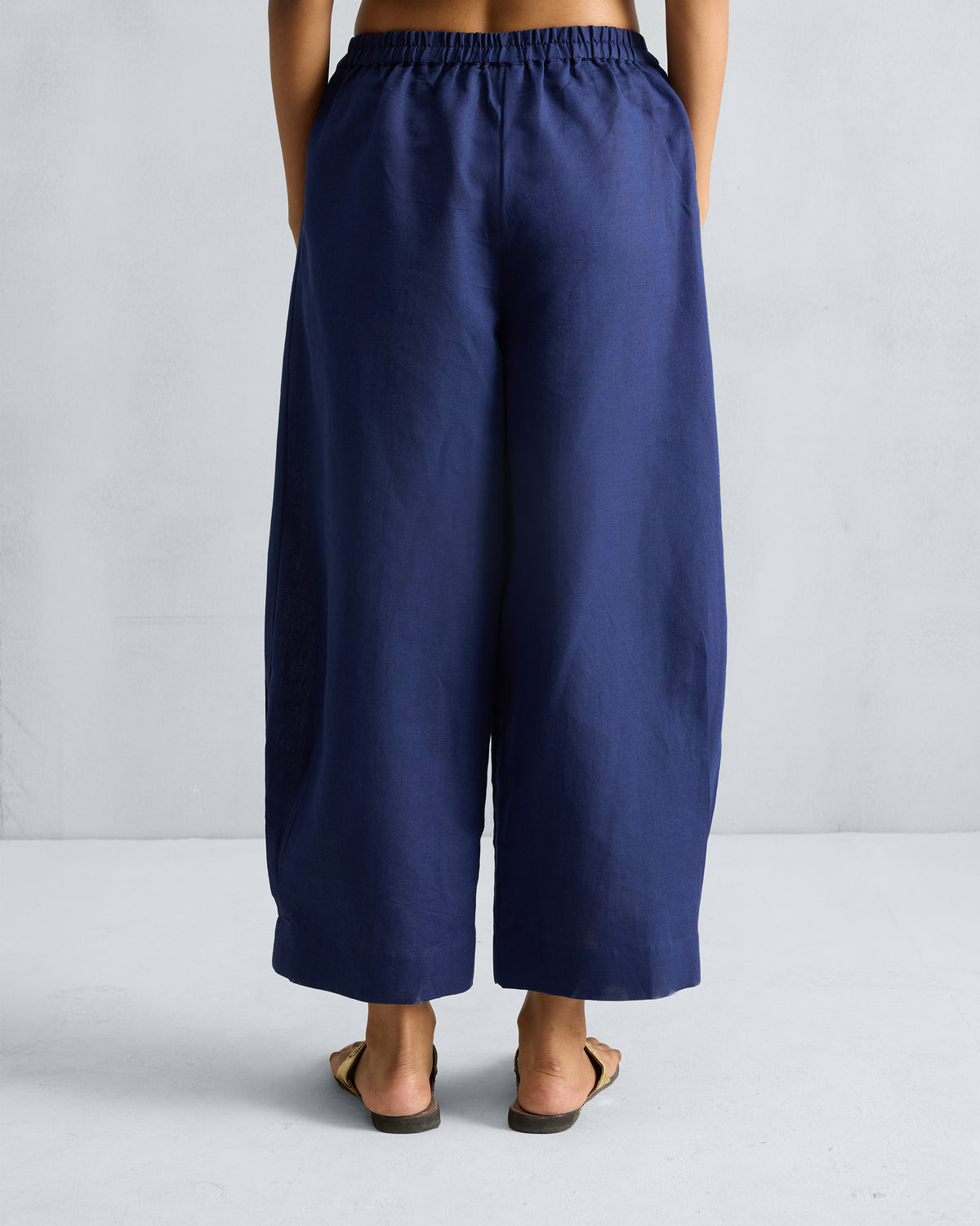 Back of ink blue Serene pants with an elastic waistband and cropped wide legs.