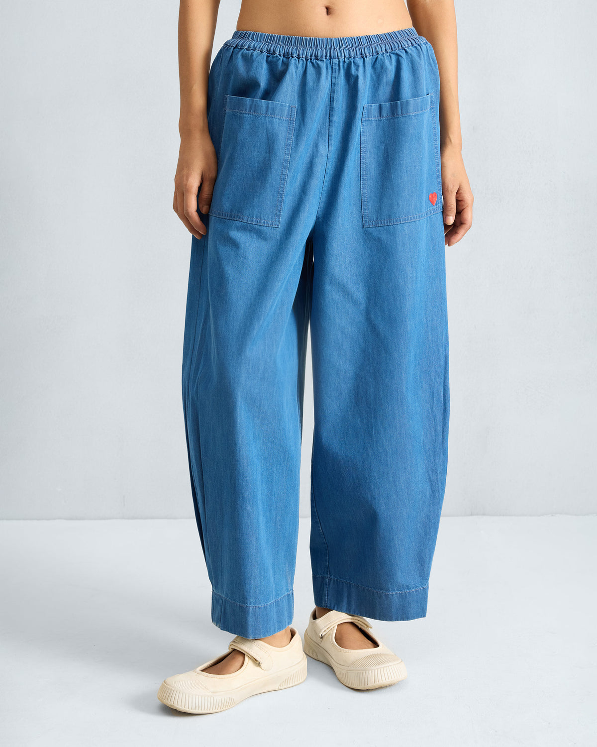 Person wearing denim Serene pants with patch pockets and a red heart.