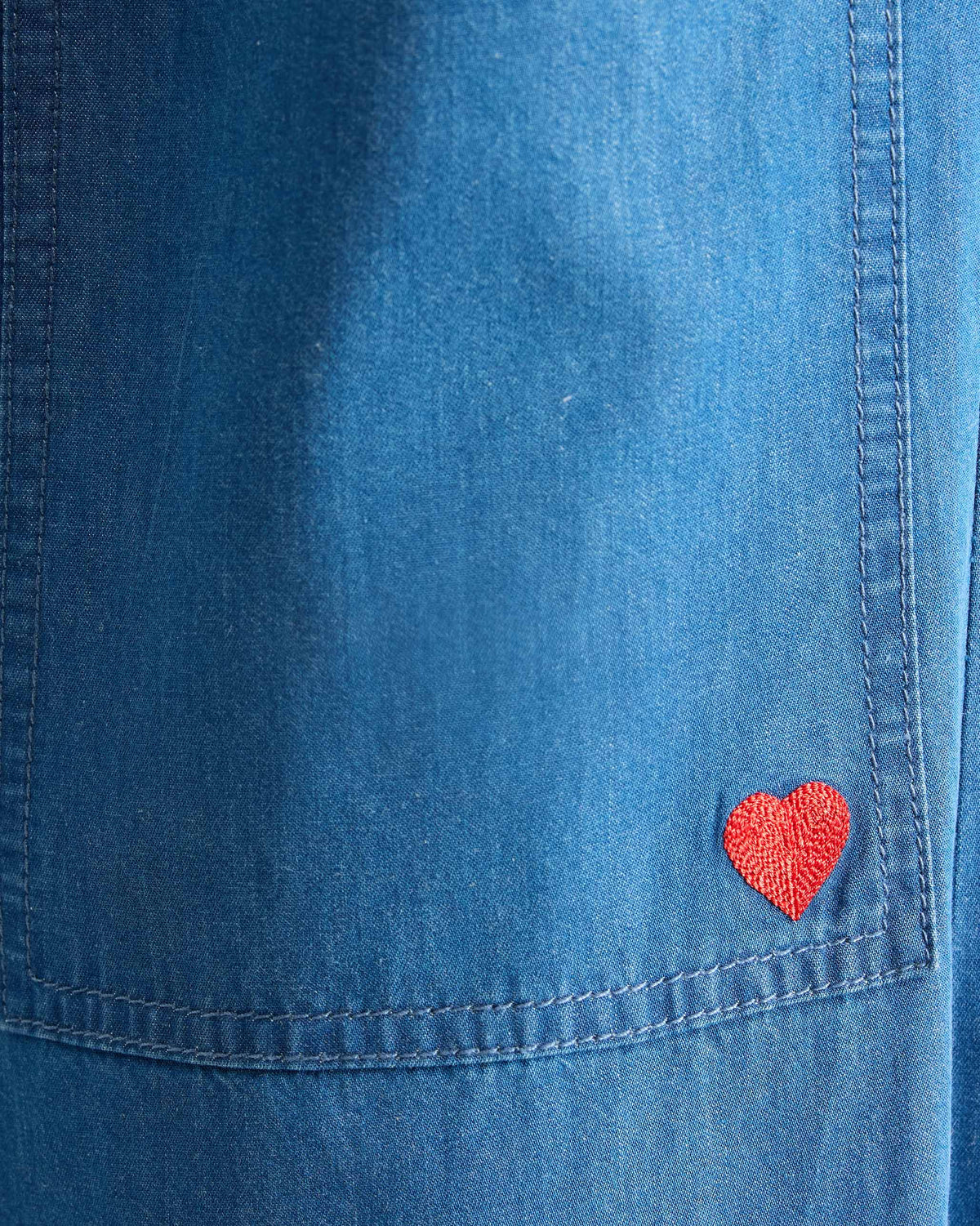 Close-up of a denim Serene pants pocket with a red heart.