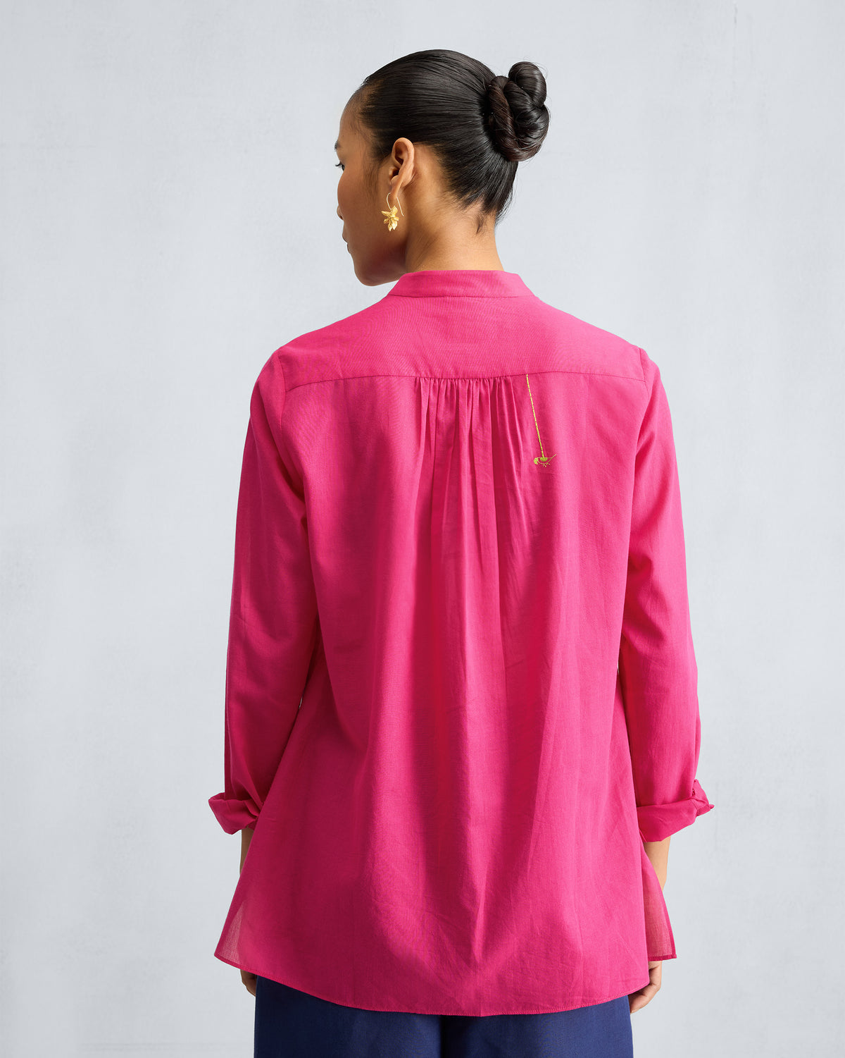 Back of a fuchsia mandarin collar top with gathers at the yoke.