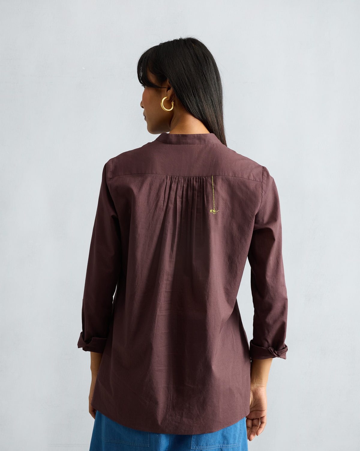 Back of a chocolate plum mandarin collar top with a green parrot.