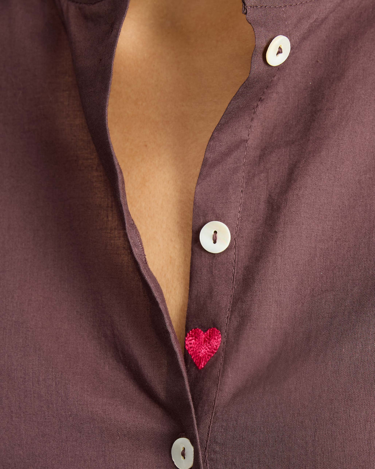 Close-up of a pink heart on a chocolate plum mandarin collar top.