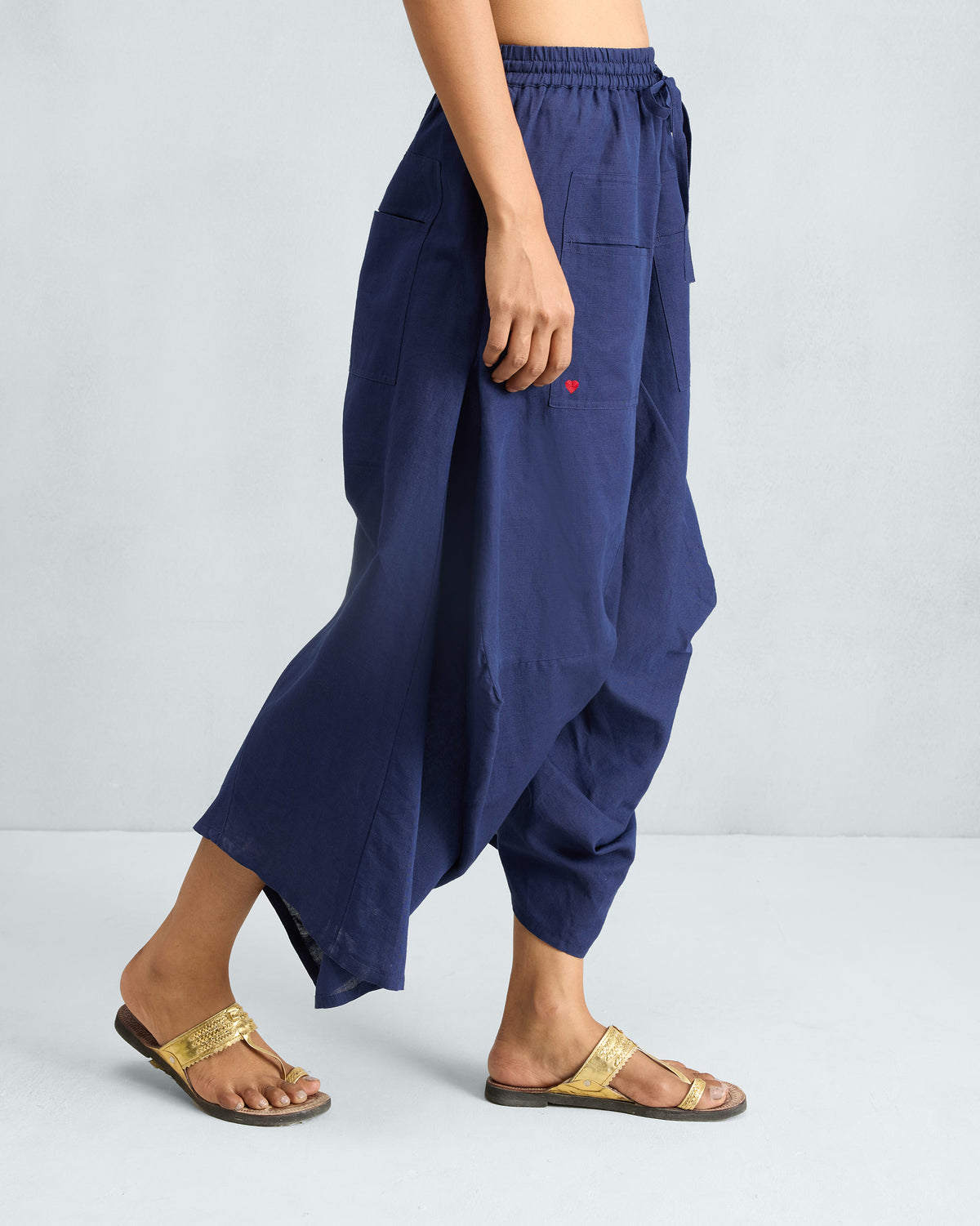 Side view of ink blue Yoka Trousers in a flared silhouette.
