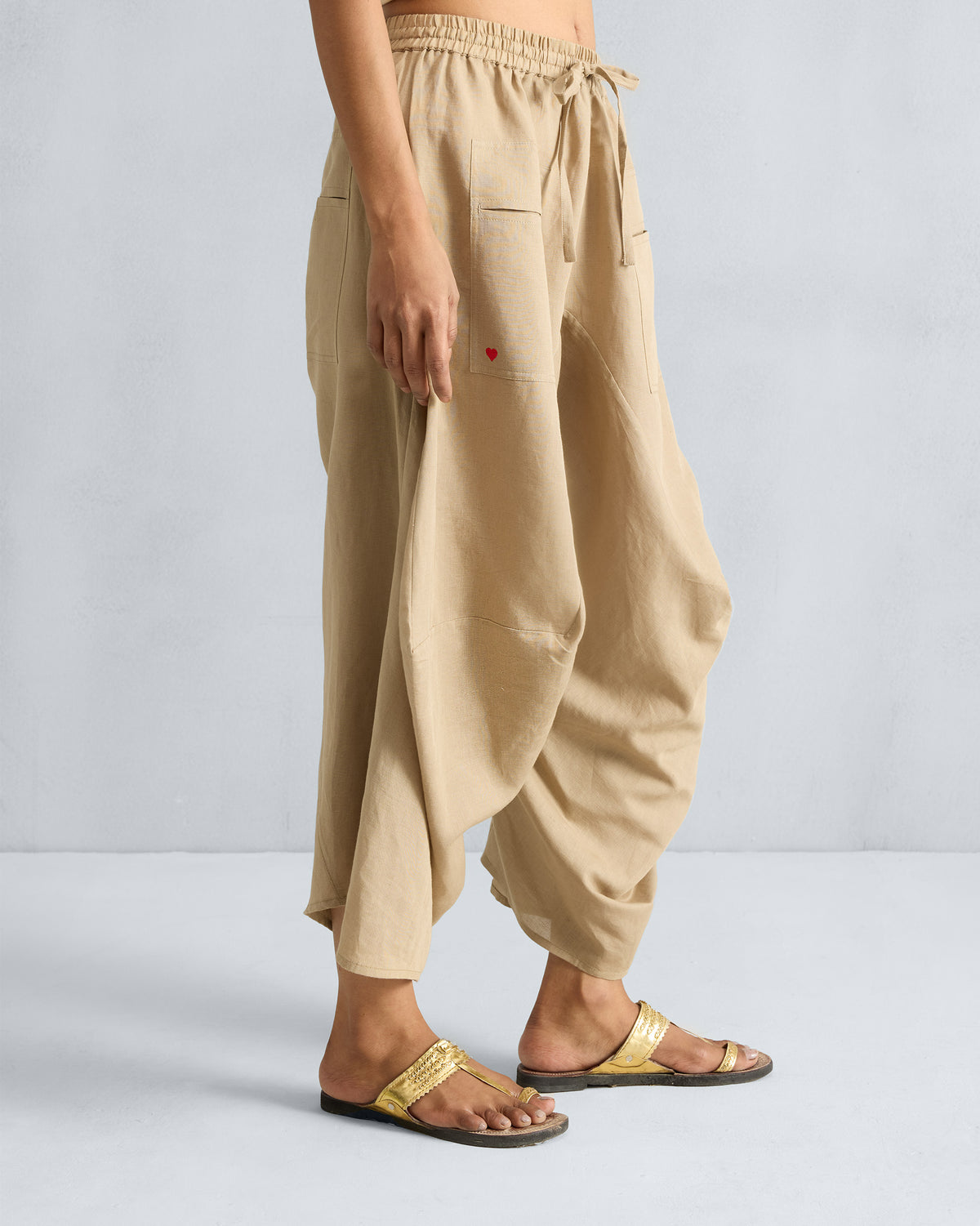Side view of beige Yoka Trousers showing a small red heart on the pocket.