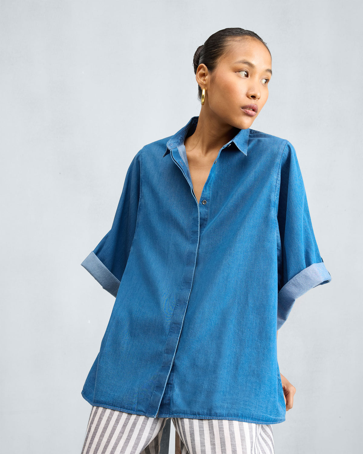 Person wearing a blue denim drop armhole shirt with wide sleeves.