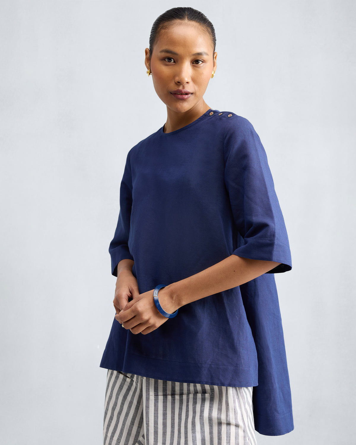 Person wearing an ink blue High Slit Top with buttons on the left shoulder.