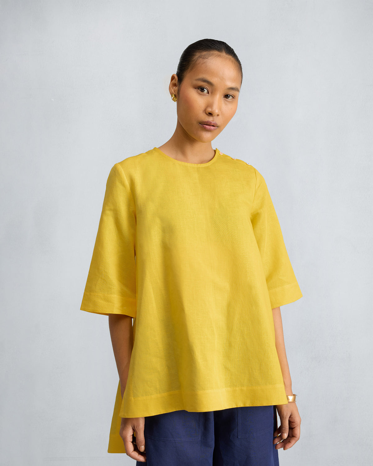 Person wearing a yellow High Slit Top with a high-low hem and shoulder buttons.