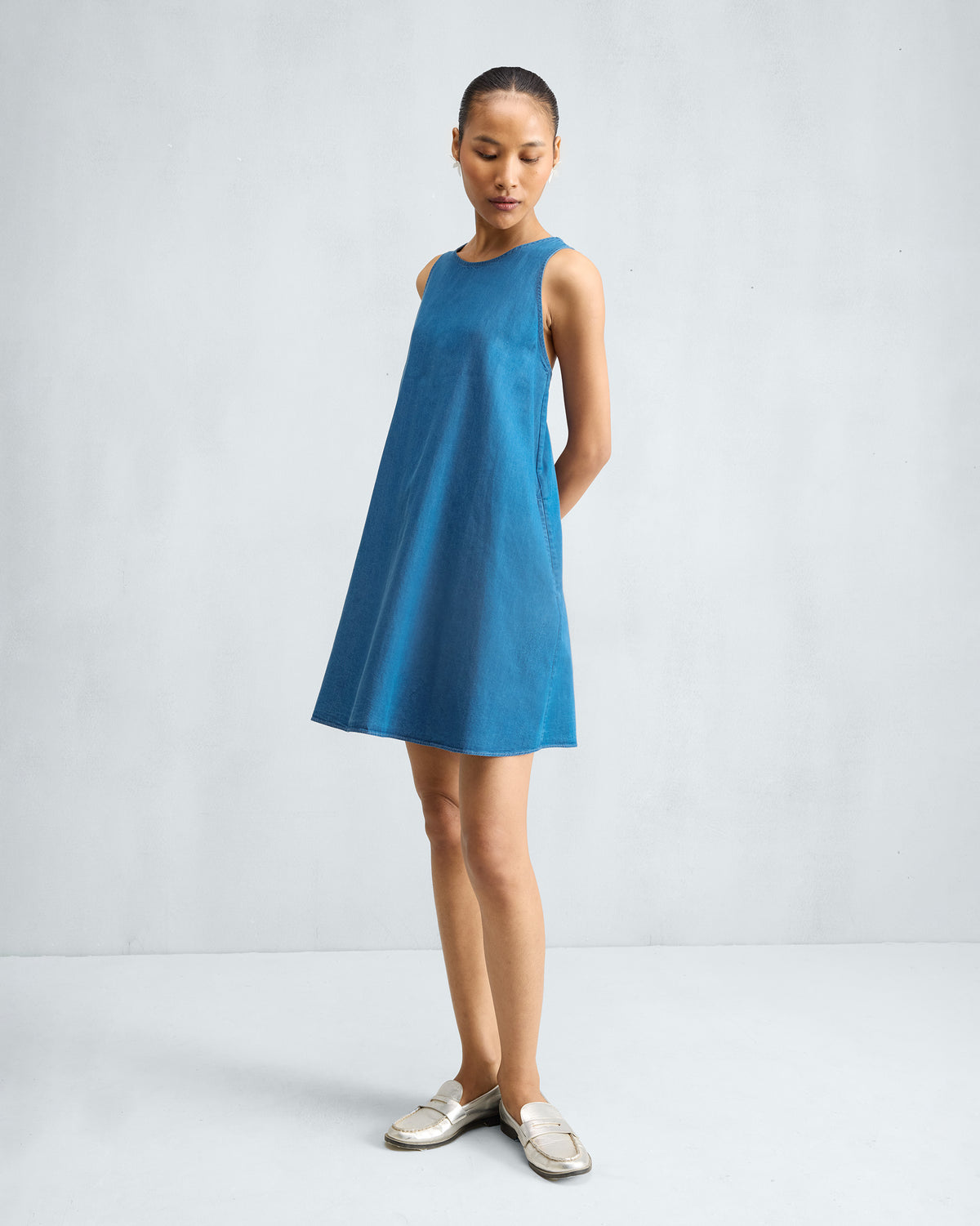 Person wearing a denim short racerback dress at a slight angle.