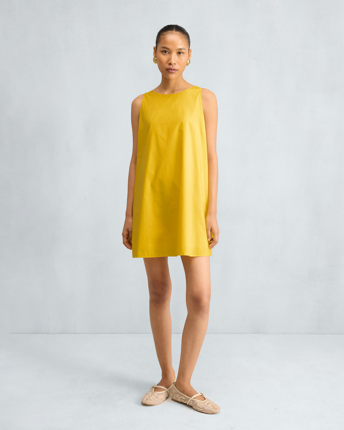 Person wearing a yellow short racerback dress.