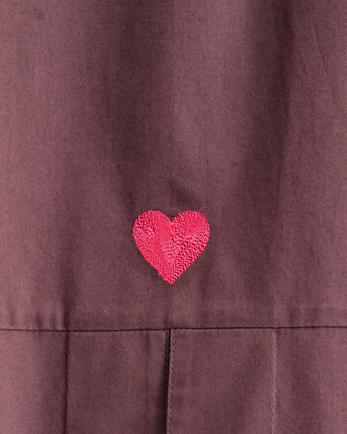 Close-up of a pink heart embroidery on a chocolate plum Cirrus shirt.