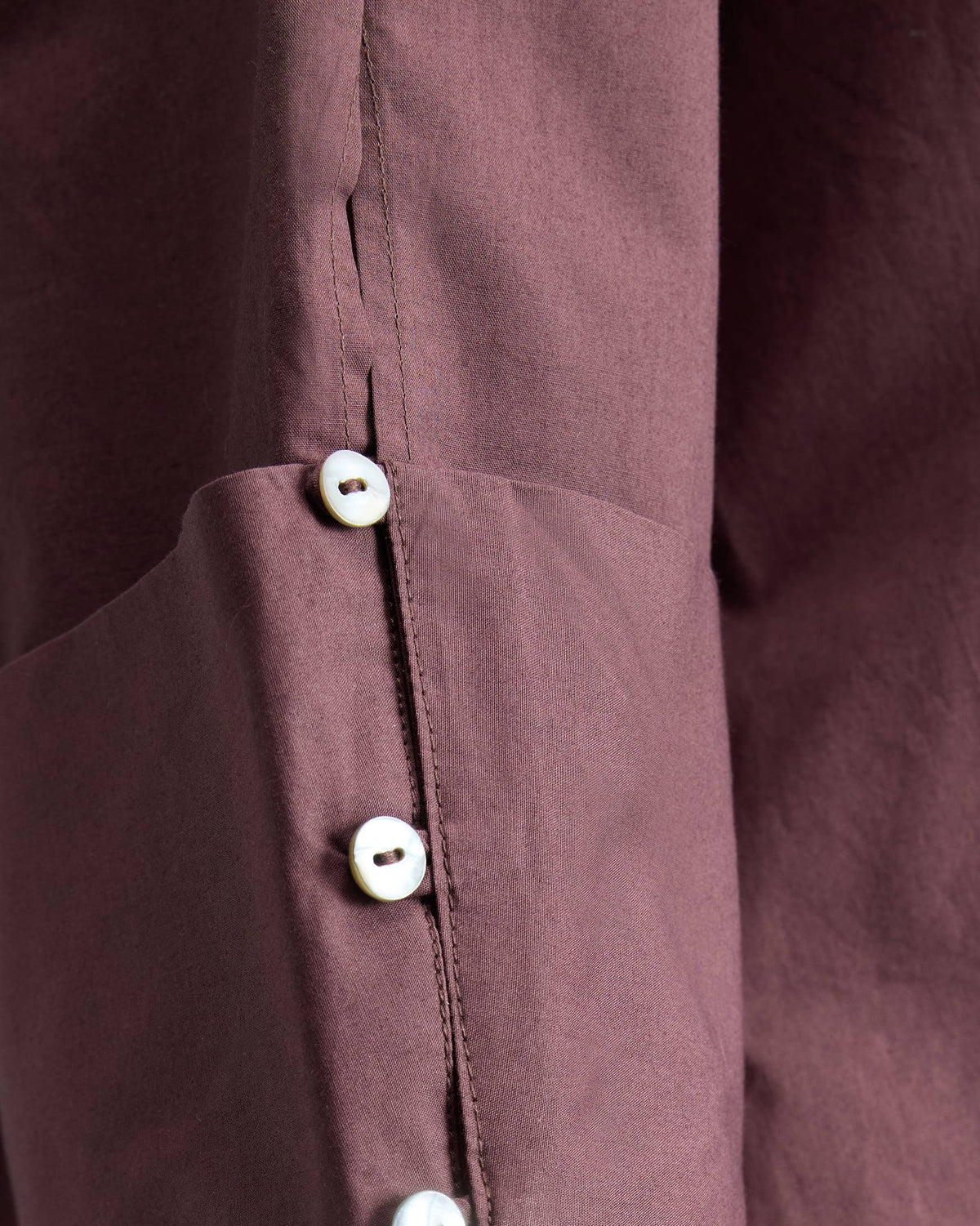 Close-up of pearl buttons on the cuff of a chocolate plum Cirrus shirt.
