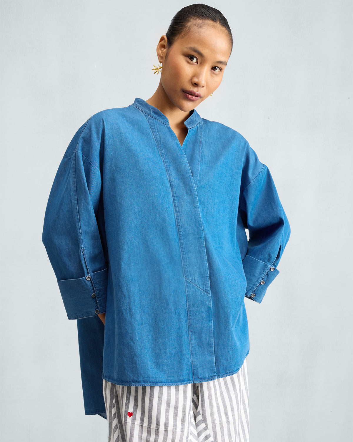 Person wearing a blue denim Cirrus shirt with a high-low hem.
