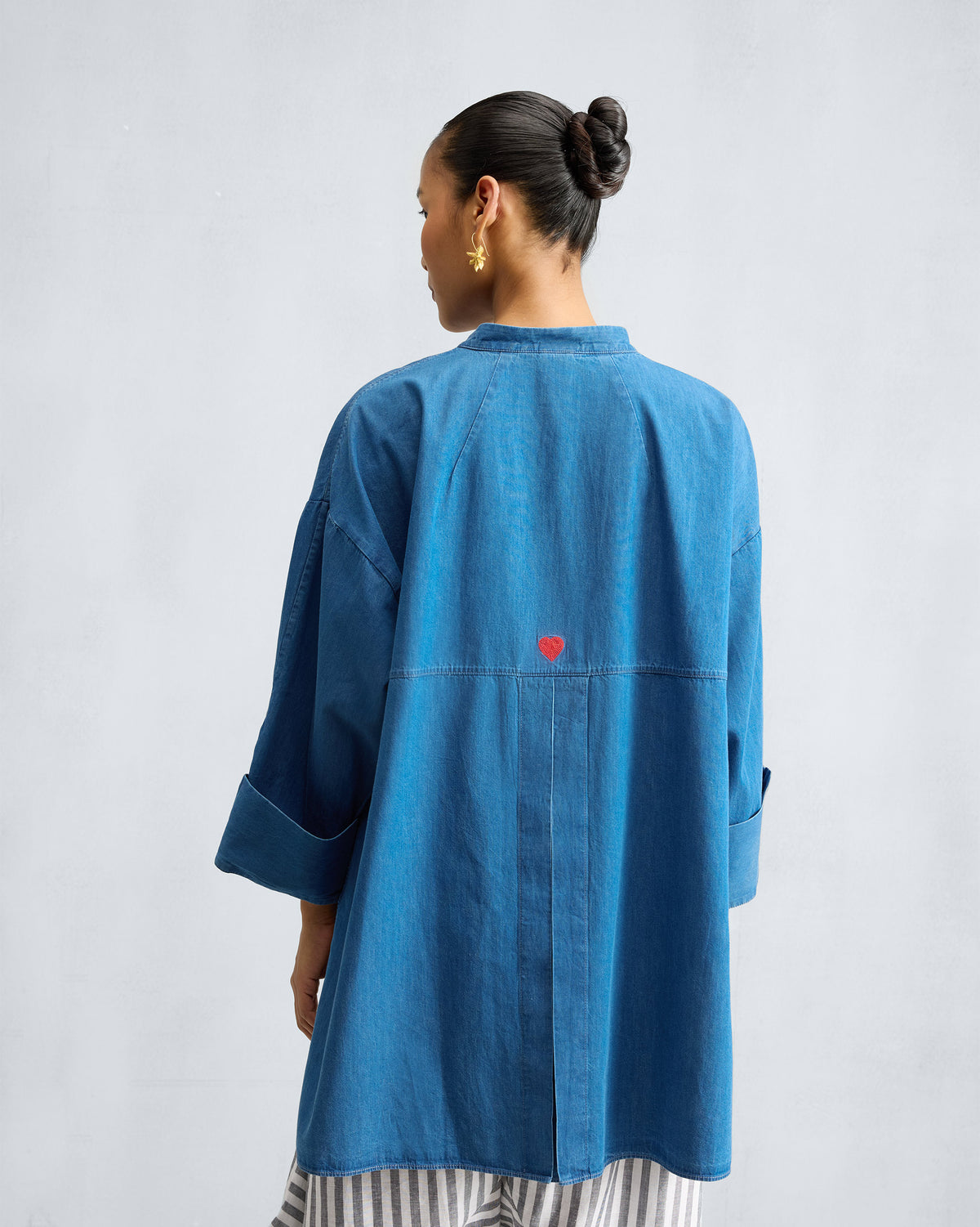 Back of a blue denim Cirrus shirt with a red heart embroidery.