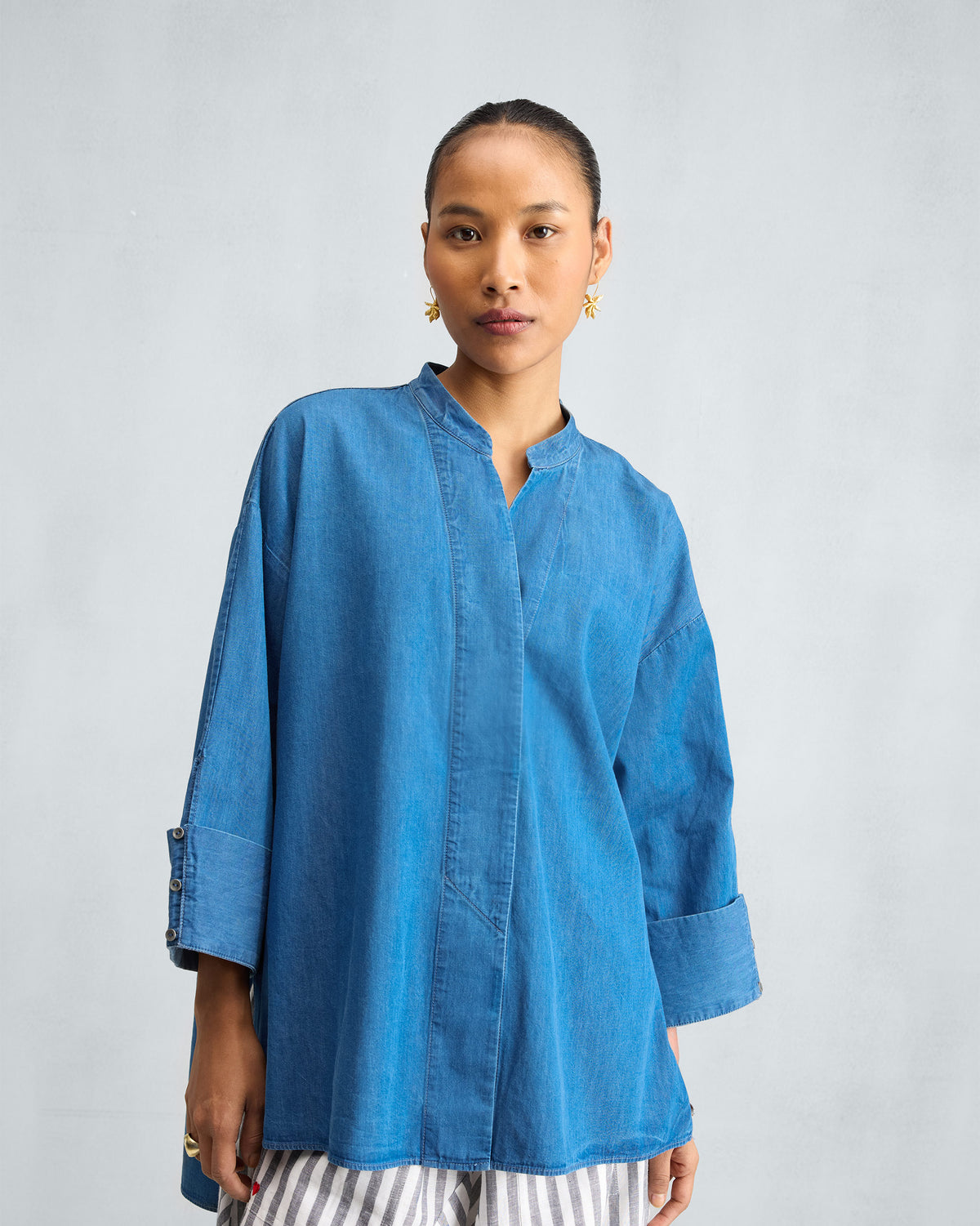Person wearing a blue denim Cirrus shirt with a mandarin collar.