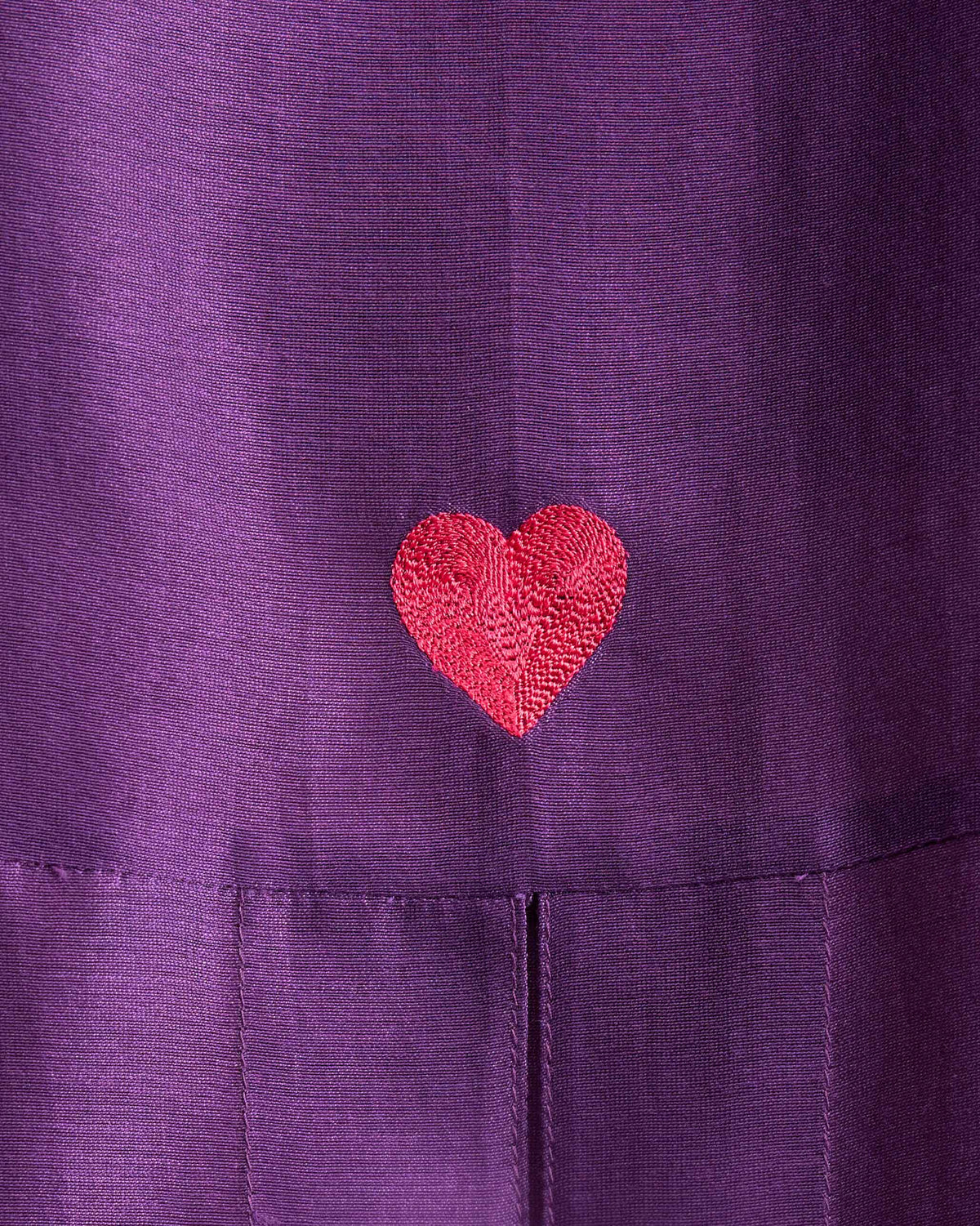 Close-up of a red embroidered heart on a purple Cirrus shirt.