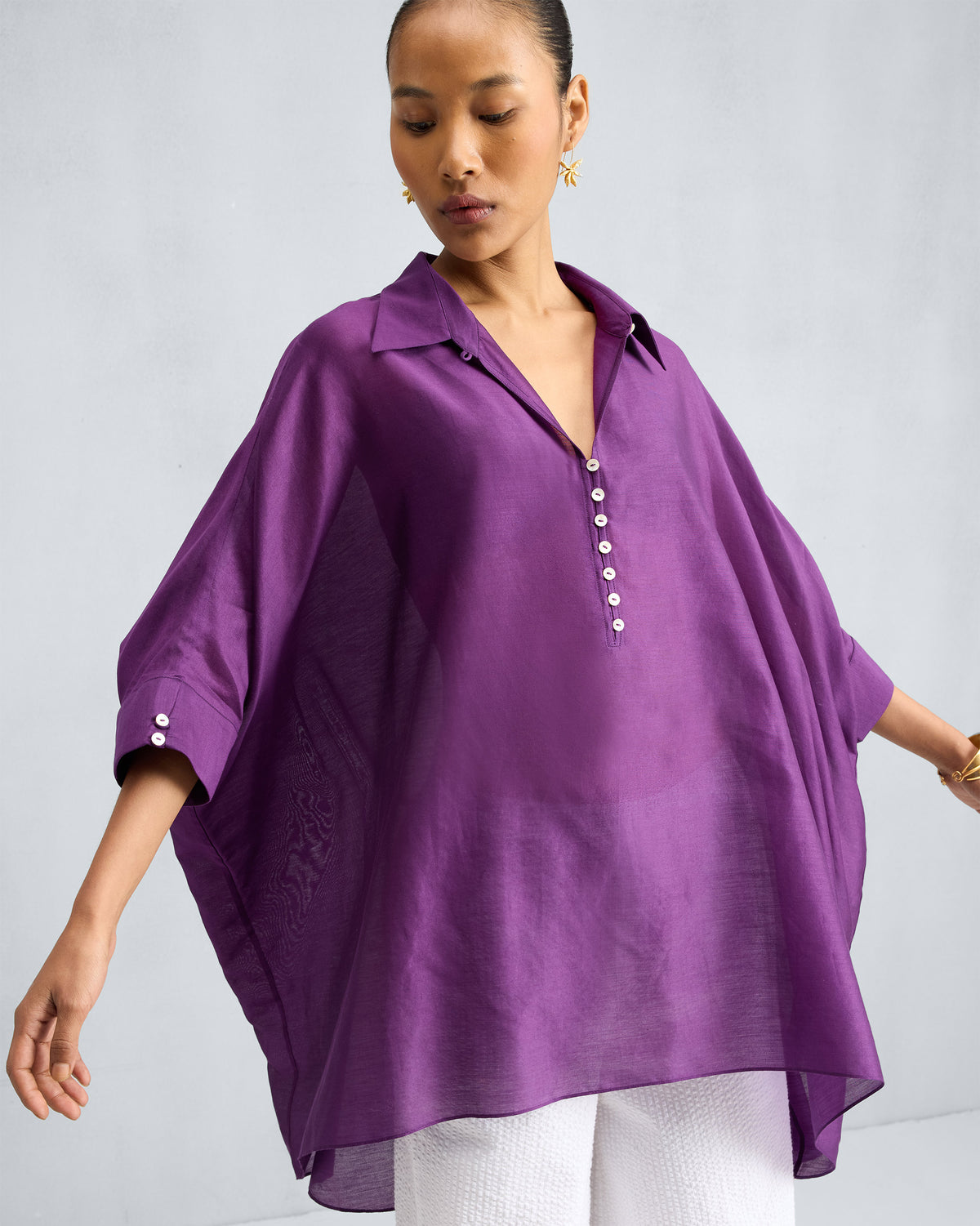 Person wearing a purple Hala Tunic with wide sleeves and a collared V-neck.
